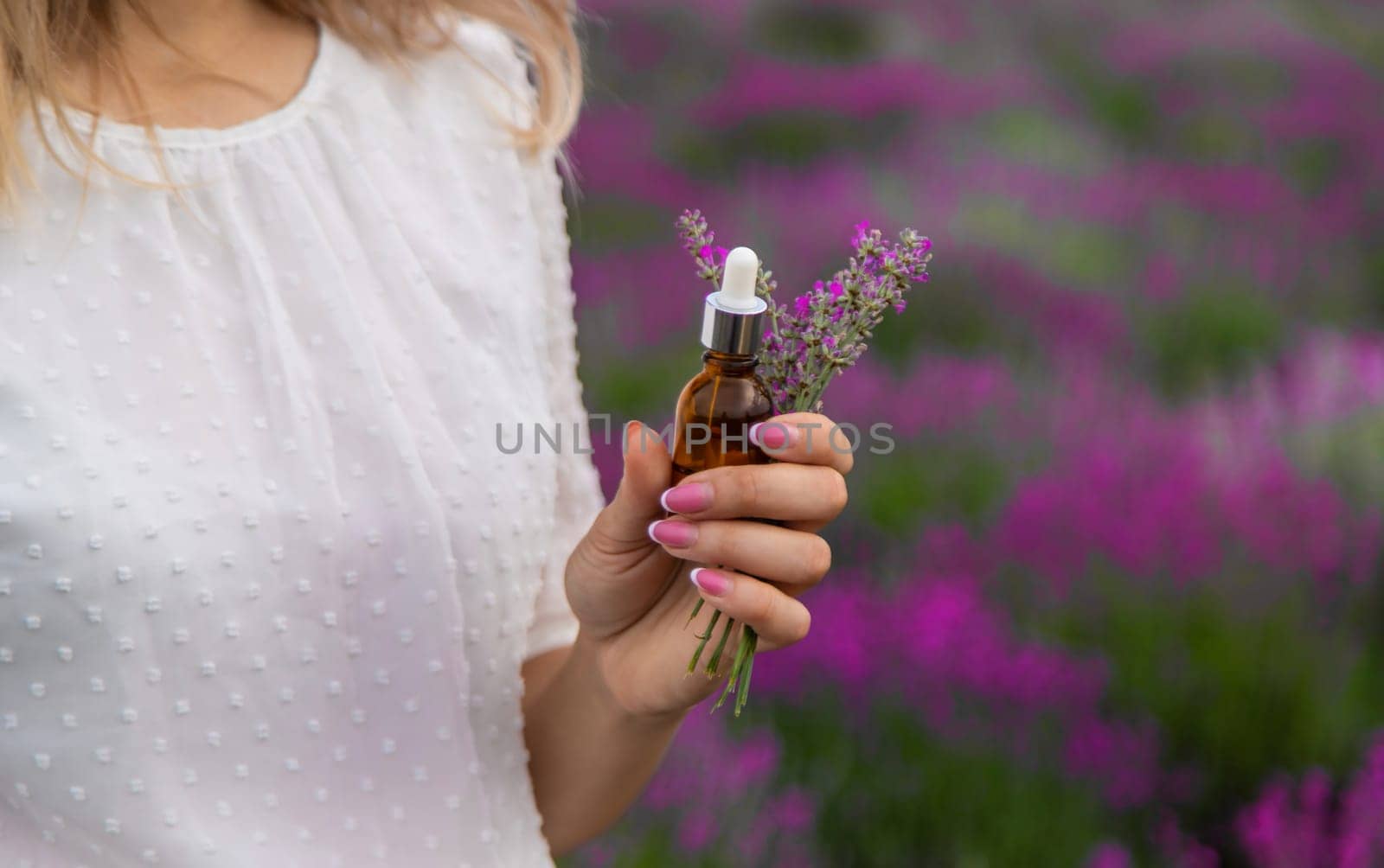 Woman in lavender field holding essential oil in her hands