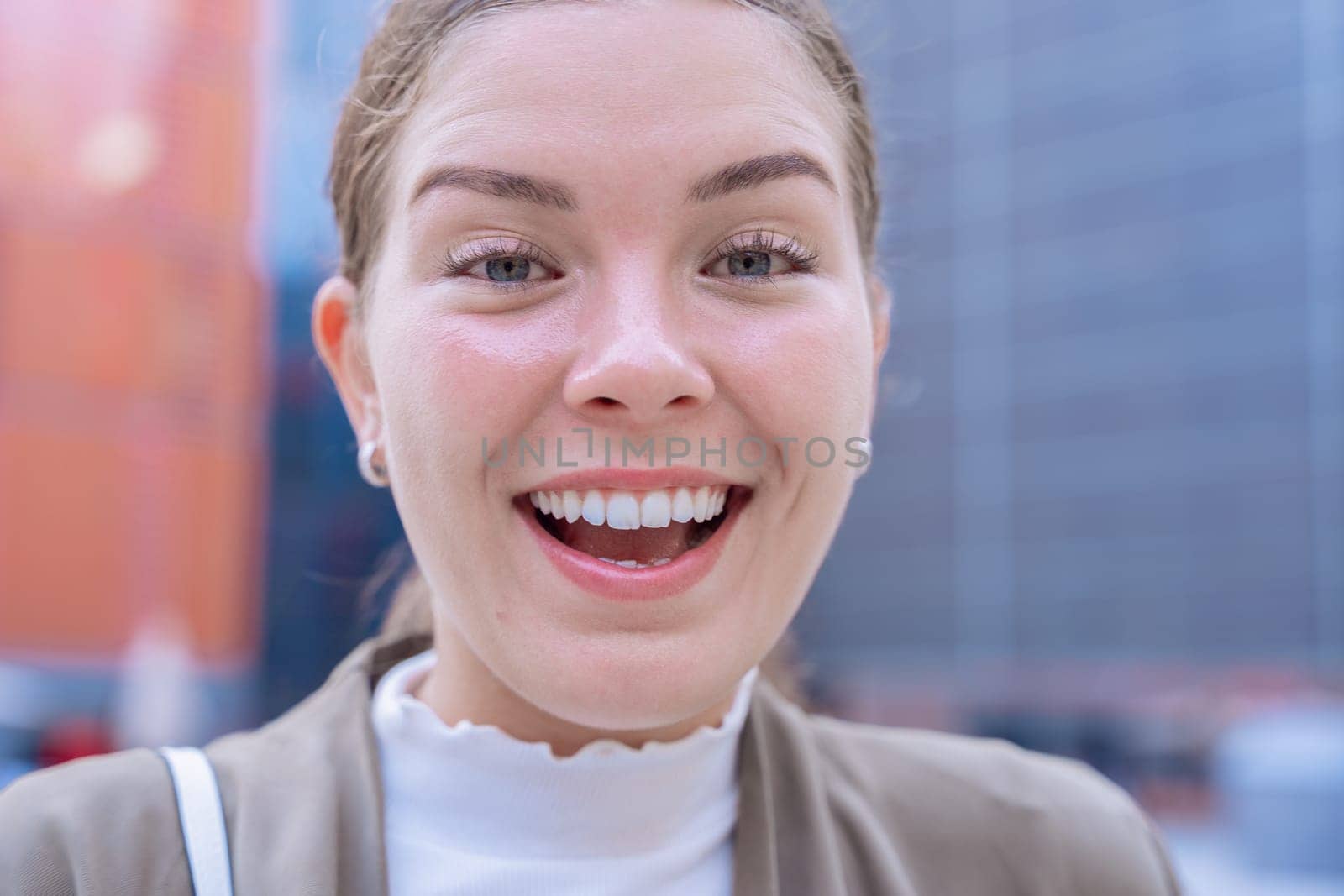 Young Caucasian businesswoman looks at the camera with a radiant smile.She radiates confidence,happiness, and positivity, making her an ideal image for lifestyle, fashion, and personal branding topics