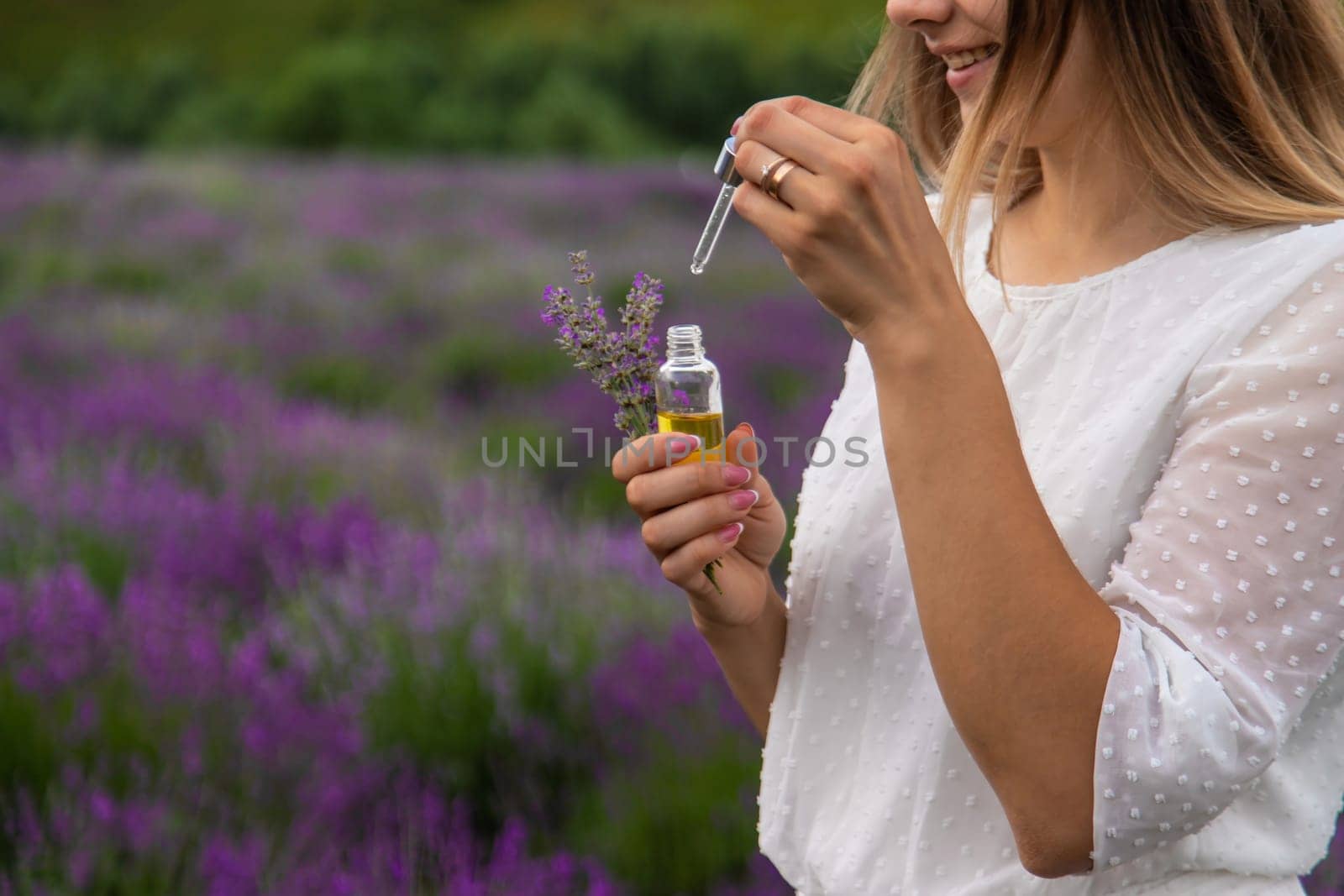 Woman in lavender field holding essential oil in her hands