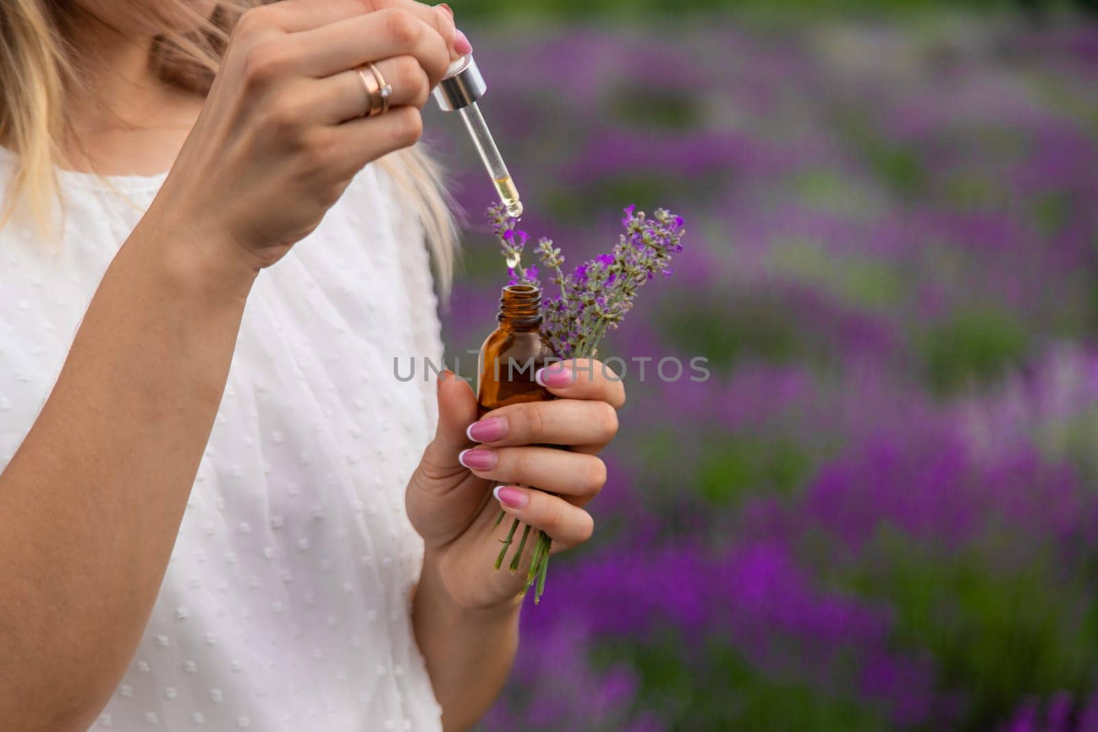 Woman in lavender field holding essential oil in her hands