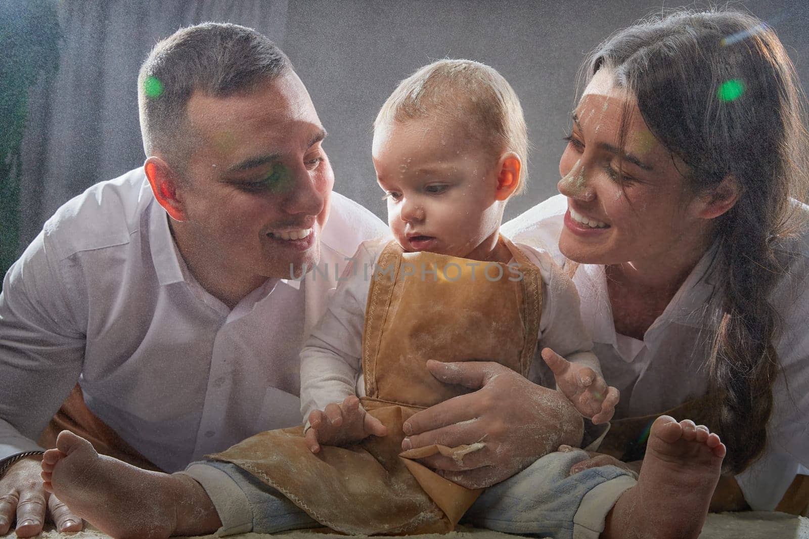 A family enjoys a fun cooking session, playfully covered in flour while engaging with their little ones in warm kitchen