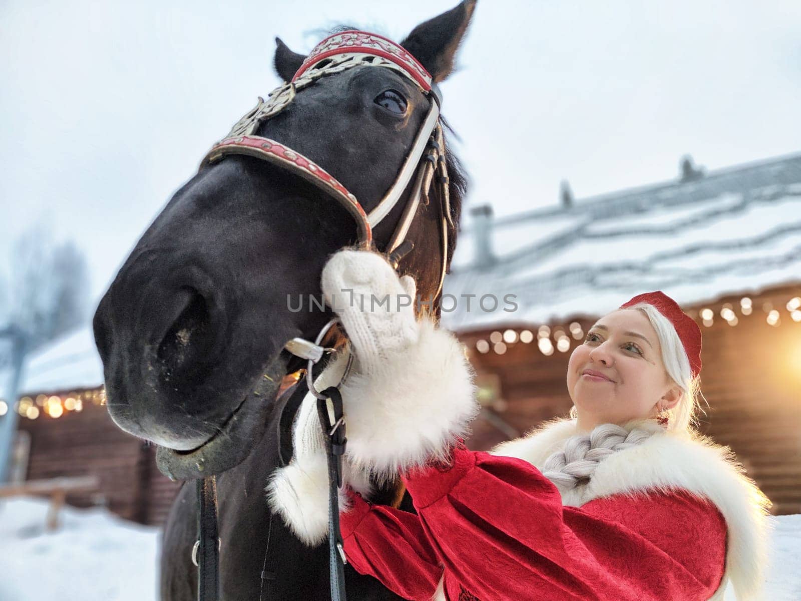 A beautiful girl dressed in traditional Russian attire enjoys a festive photoshoot with a horse during Maslenitsa.