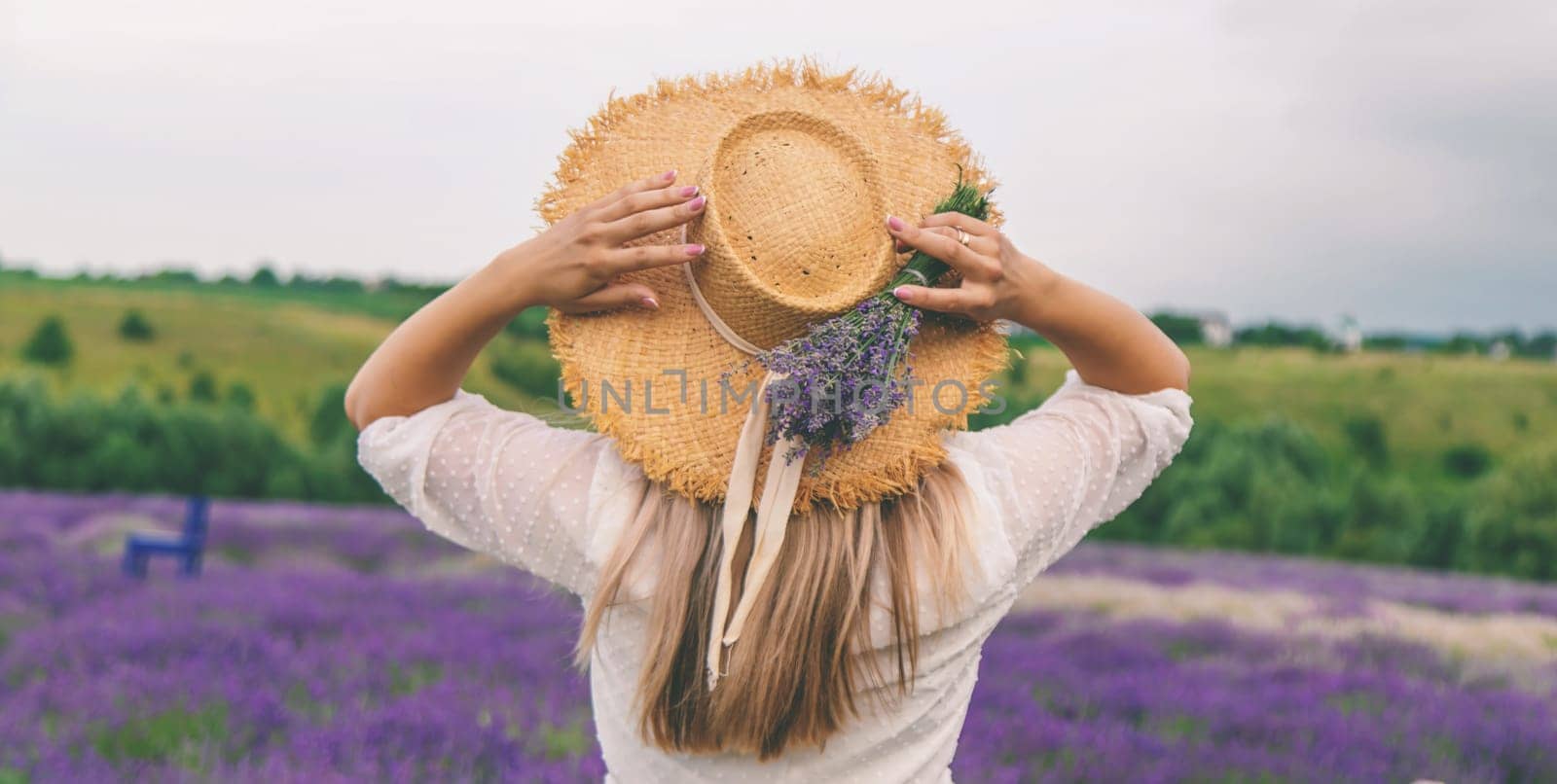 Woman in lavender field. Happy carefree woman in white dress and straw hat walking through lavender field
