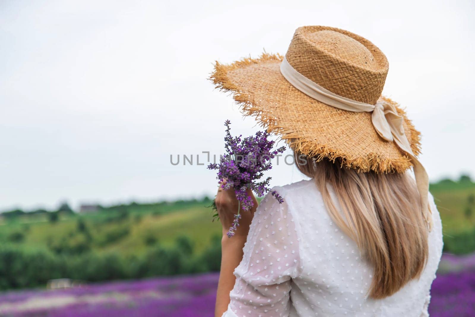 Woman in lavender field. Happy carefree woman in white dress and straw hat walking through lavender field