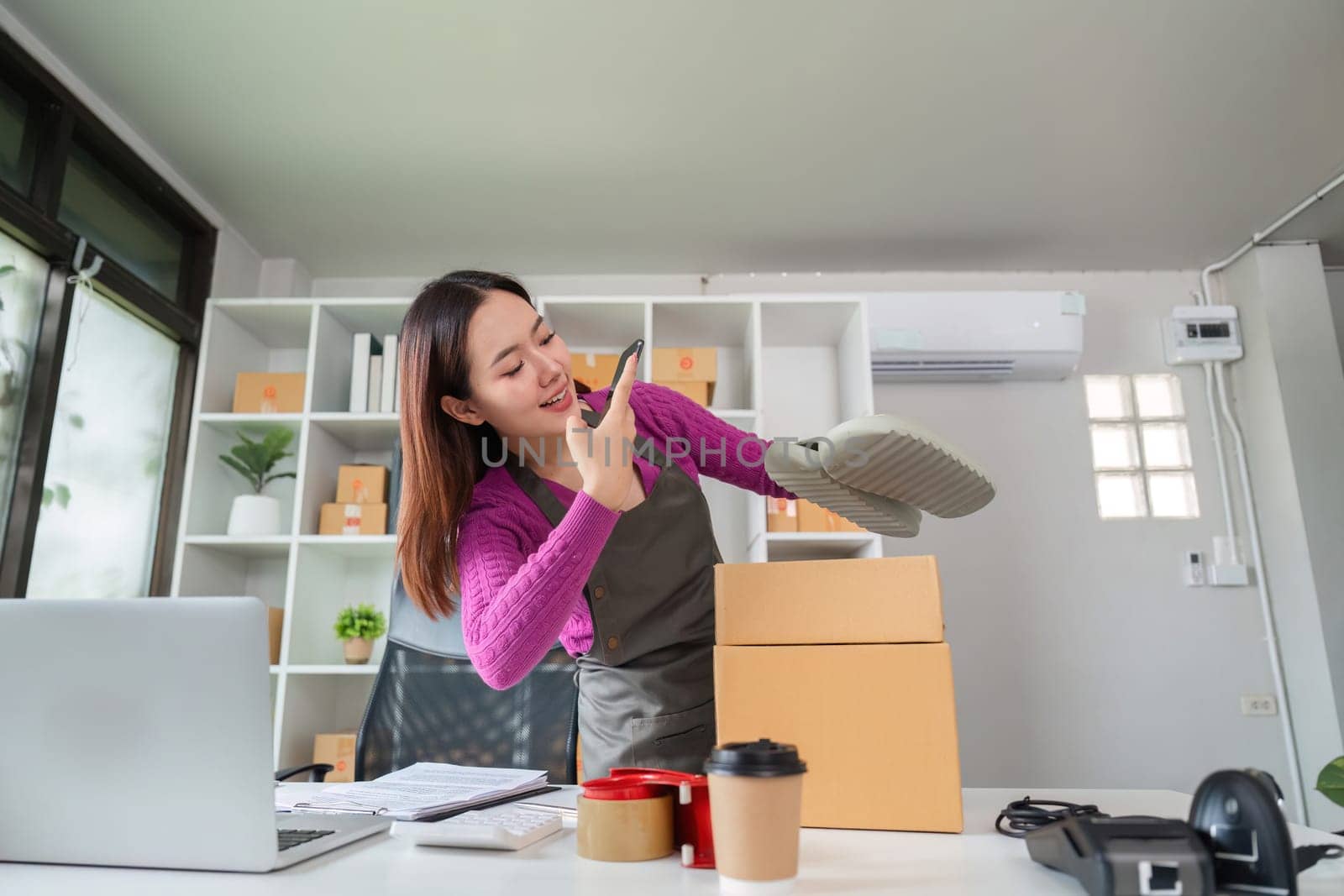 An online seller excitedly prepares a product by inspecting it before placing it in a box for shipping, showcasing the care put into fulfilling each order.