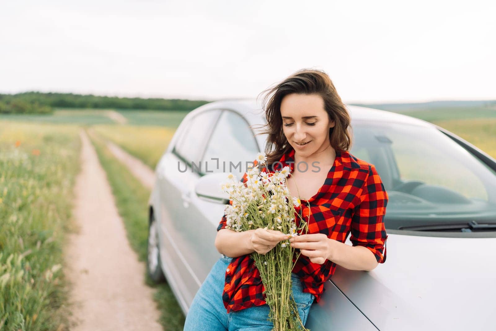 A woman is sitting on the side of a road with a bouquet of flowers in her hand