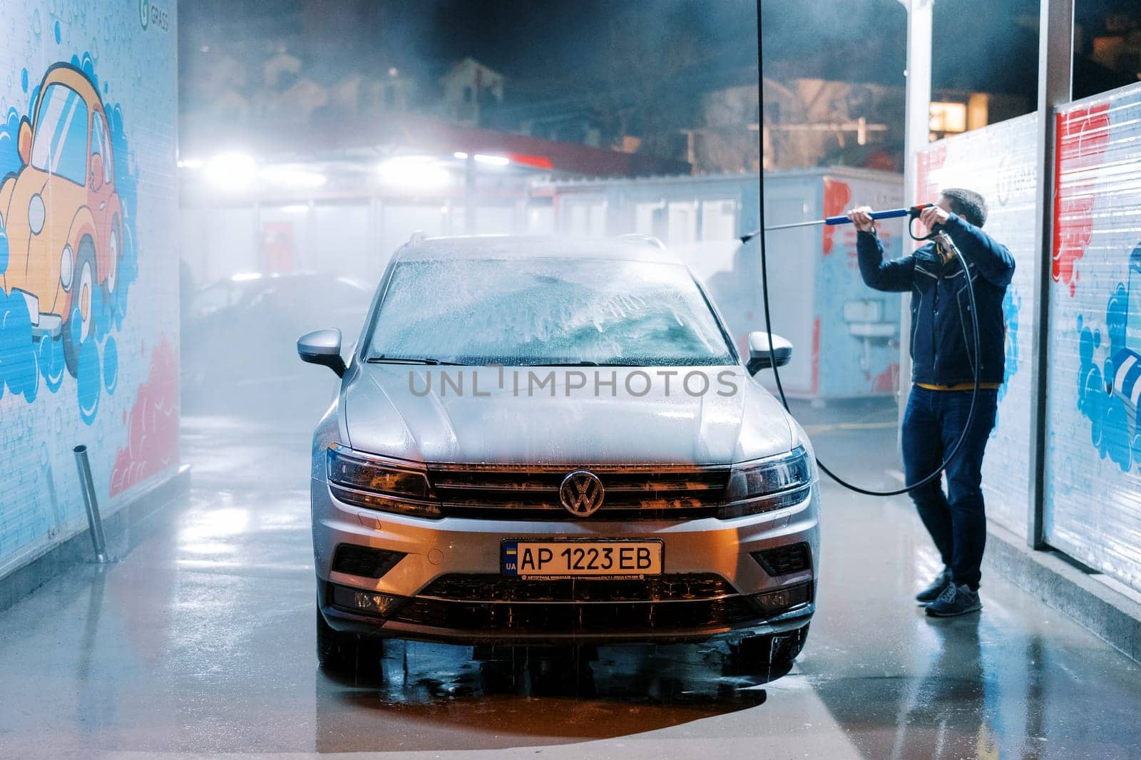 Driver washing a car with a hose at a self-service car wash. High quality photo
