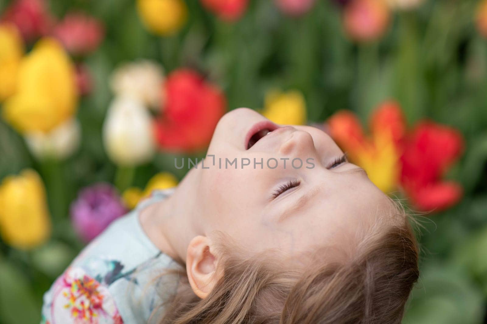 Happy girl laughs in a park with the tulips