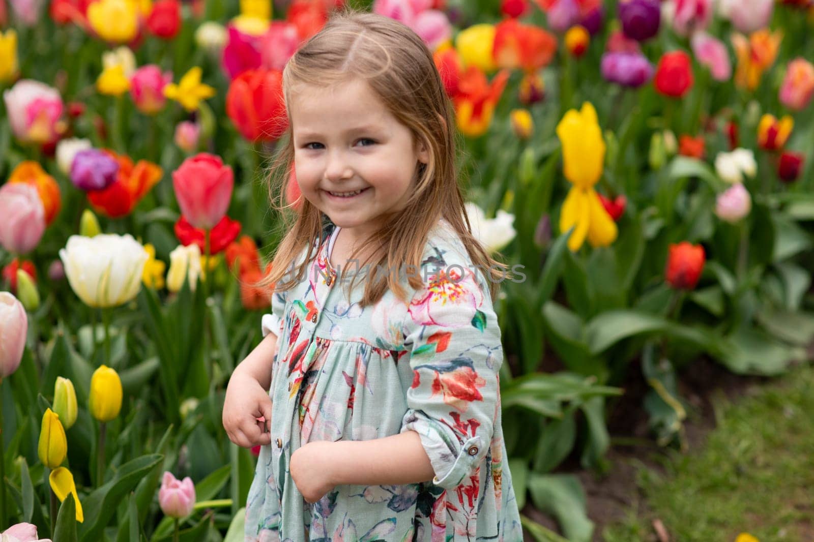 Happy girl laughs in a park with the tulips