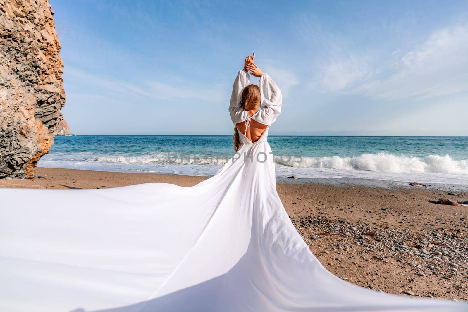 Woman beach white dress flying on Wind. Summer Vacation. A happy woman takes vacation photos to send to friends