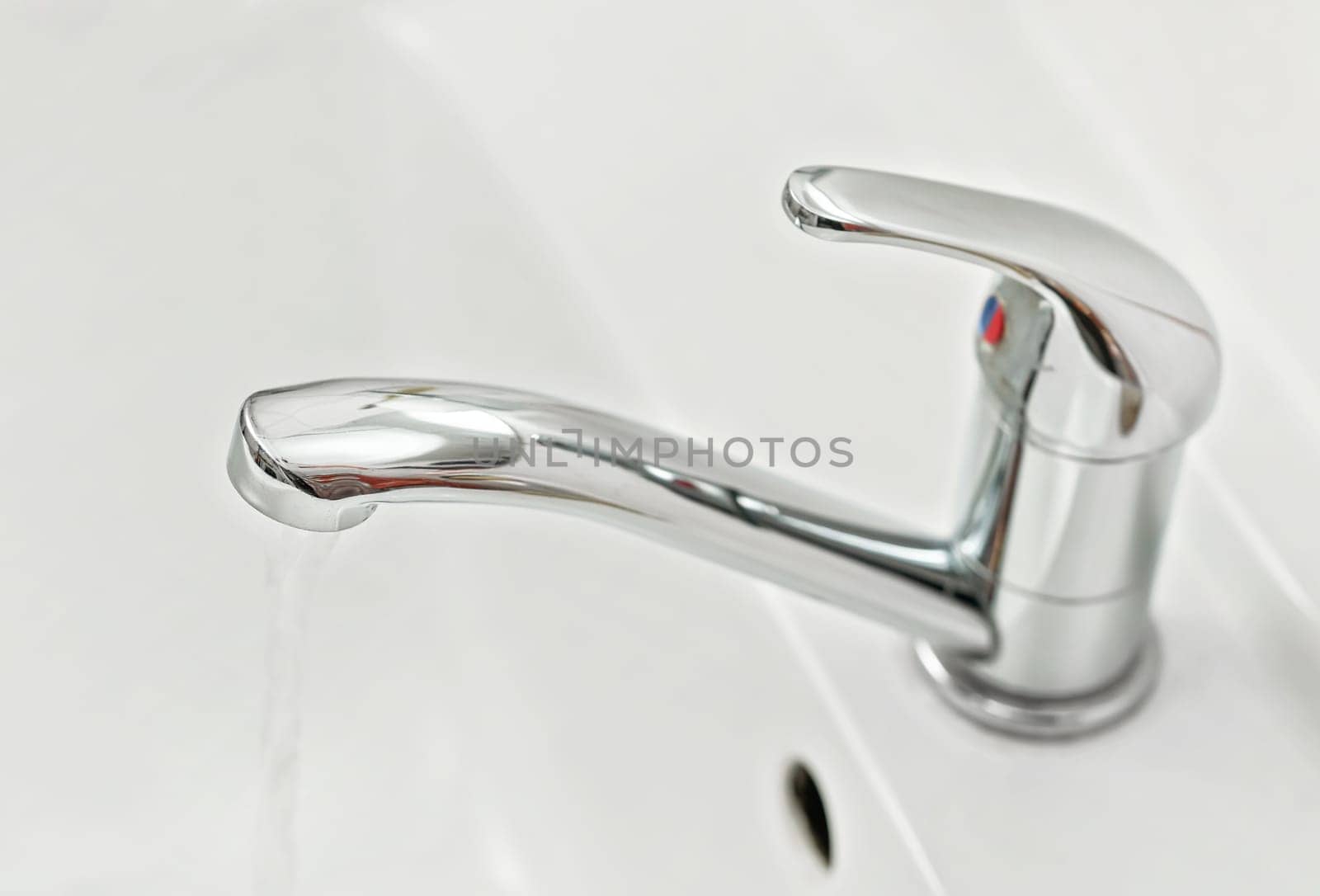 Chrome faucet tap with water flowing, closeup detail
