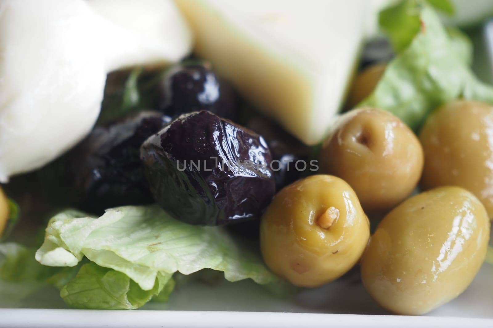 Colorful assortment of olives and greens arranged artistically on a plate.
