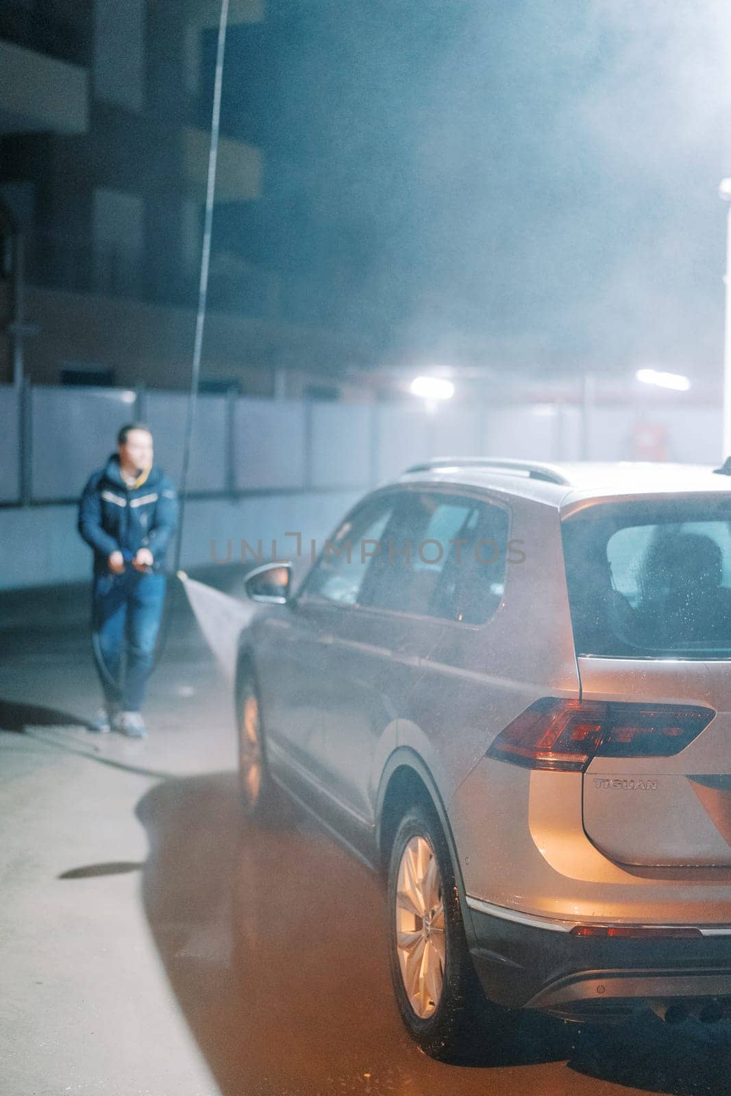 Man washing car with hose at self-service car wash. High quality photo