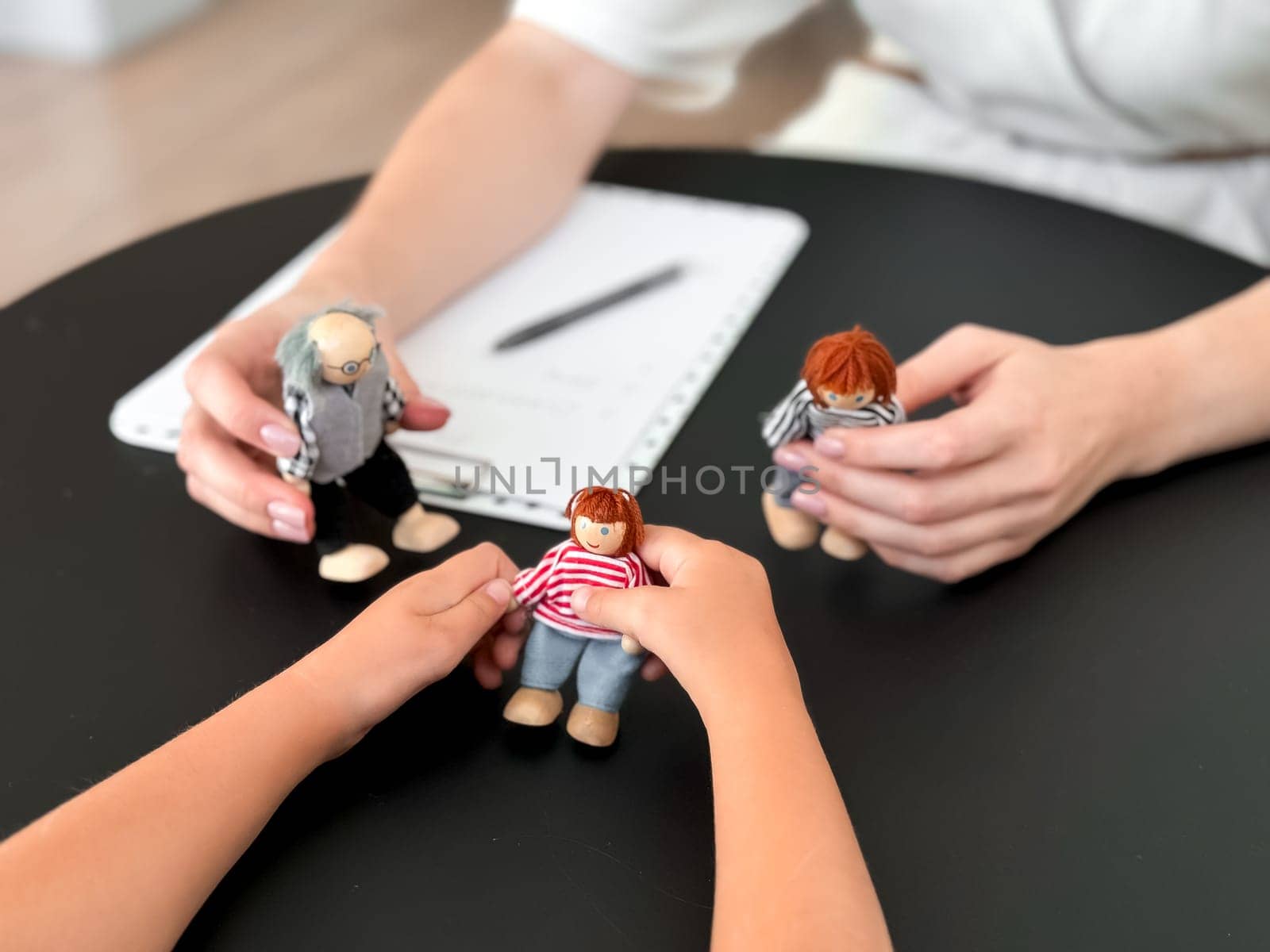 Child therapy session with puppet family interaction on table.
