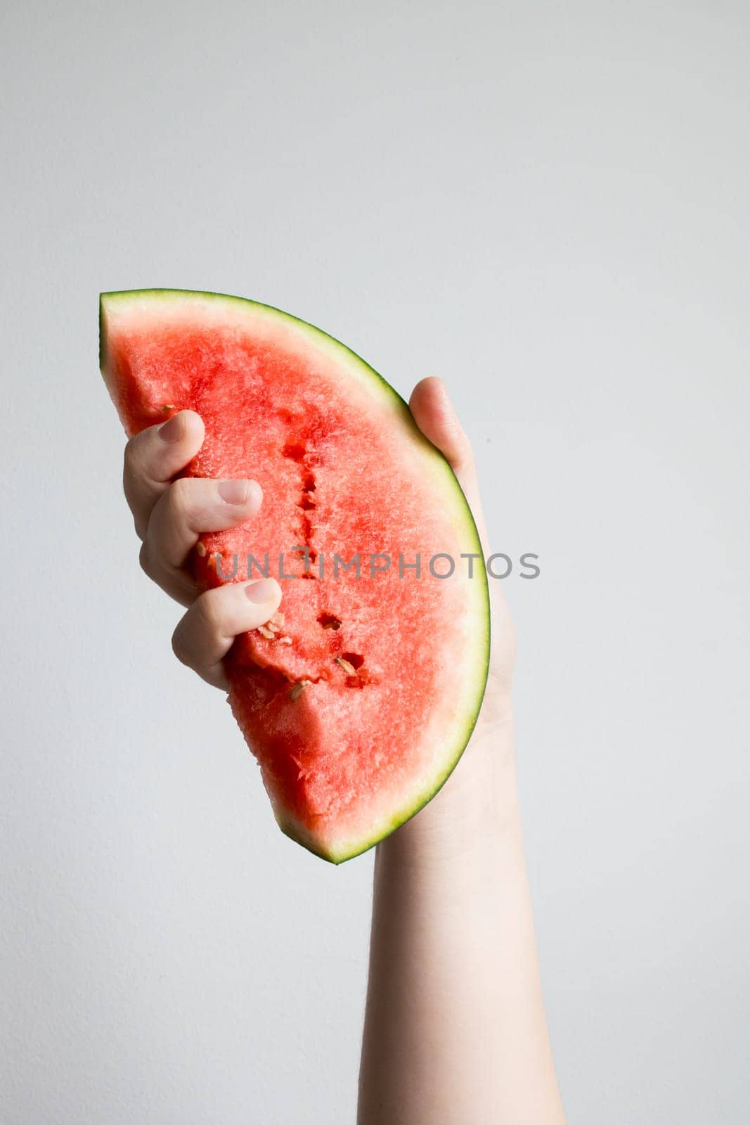 Hand holding juicy watermelon slice against white background.