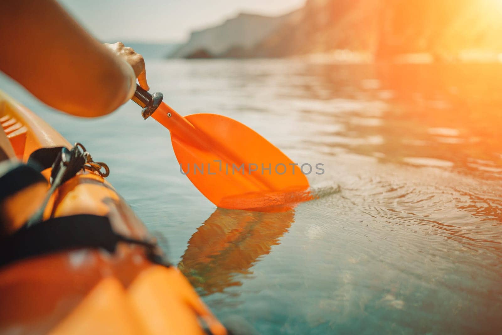 Kayak paddle sea vacation. Person paddles with orange paddle oar on kayak in sea. Leisure active lifestyle recreation activity rest tourism travel.