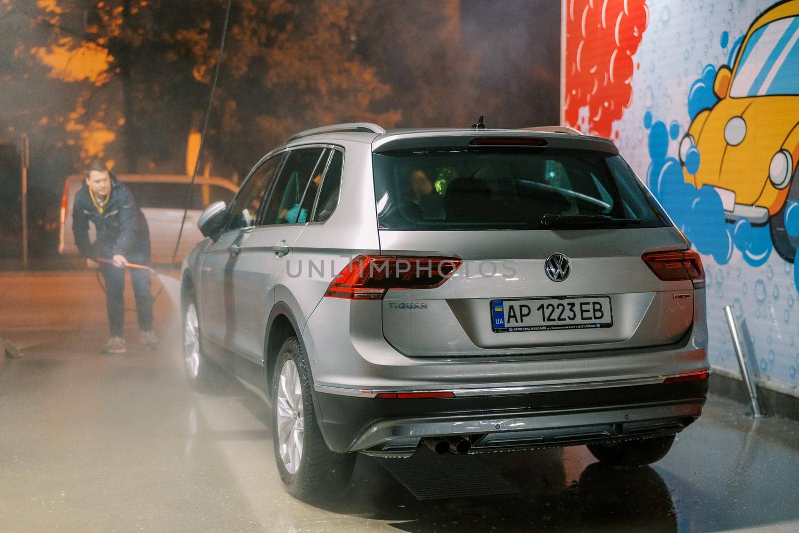 Driver washes his car with a hose at a self-service car wash. High quality photo