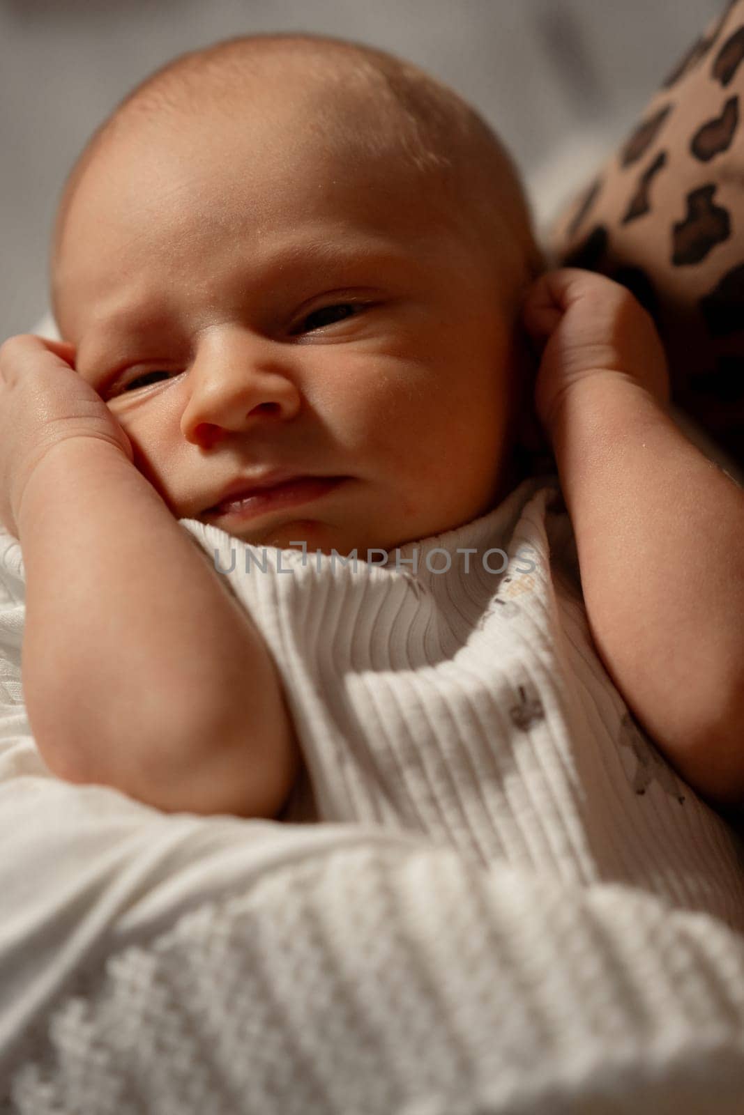 A mother lovingly holds her baby close, creating a tender moment in a warm, relaxed indoor environment with soft lighting.