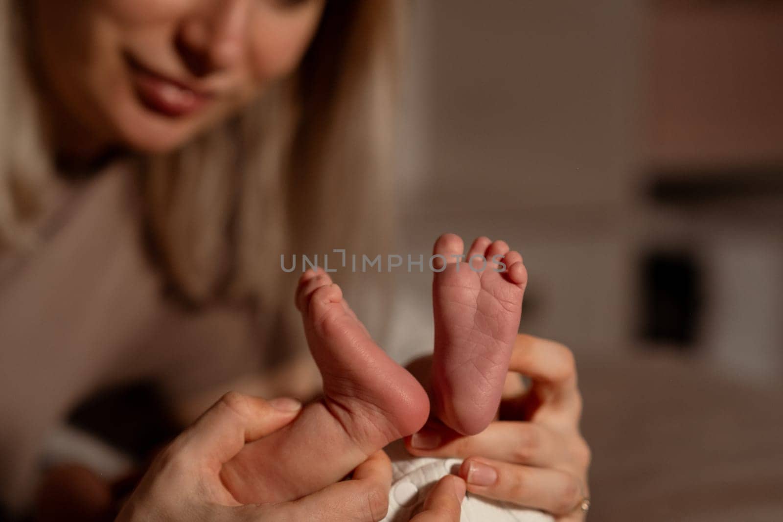 A mother lovingly cradles her babys small feet in a warm, intimate setting, creating a special bond in the early evening light.