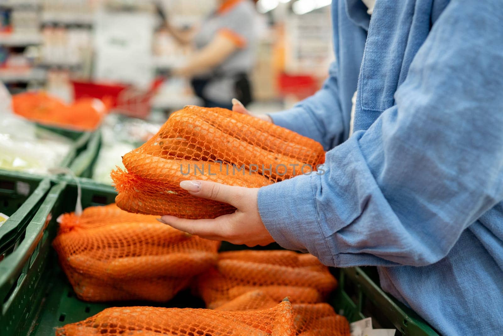 Close-Up Of Woman Grabbing Carrot In Supermarket