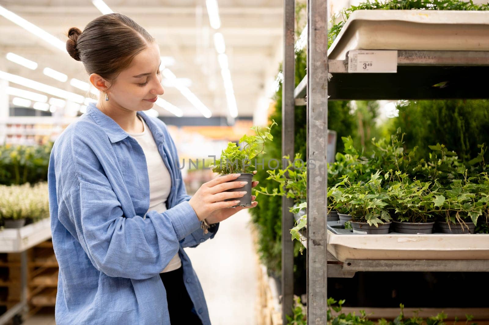 Happy Girl Choosing Potted Plant In The Supermarket