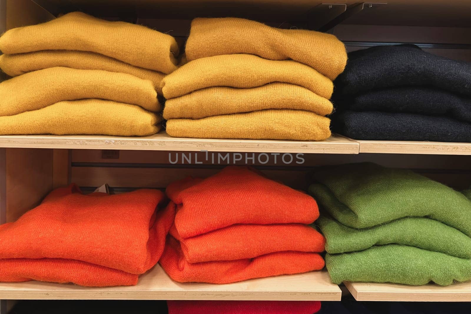 A row of folded sweaters on a shelf in the store