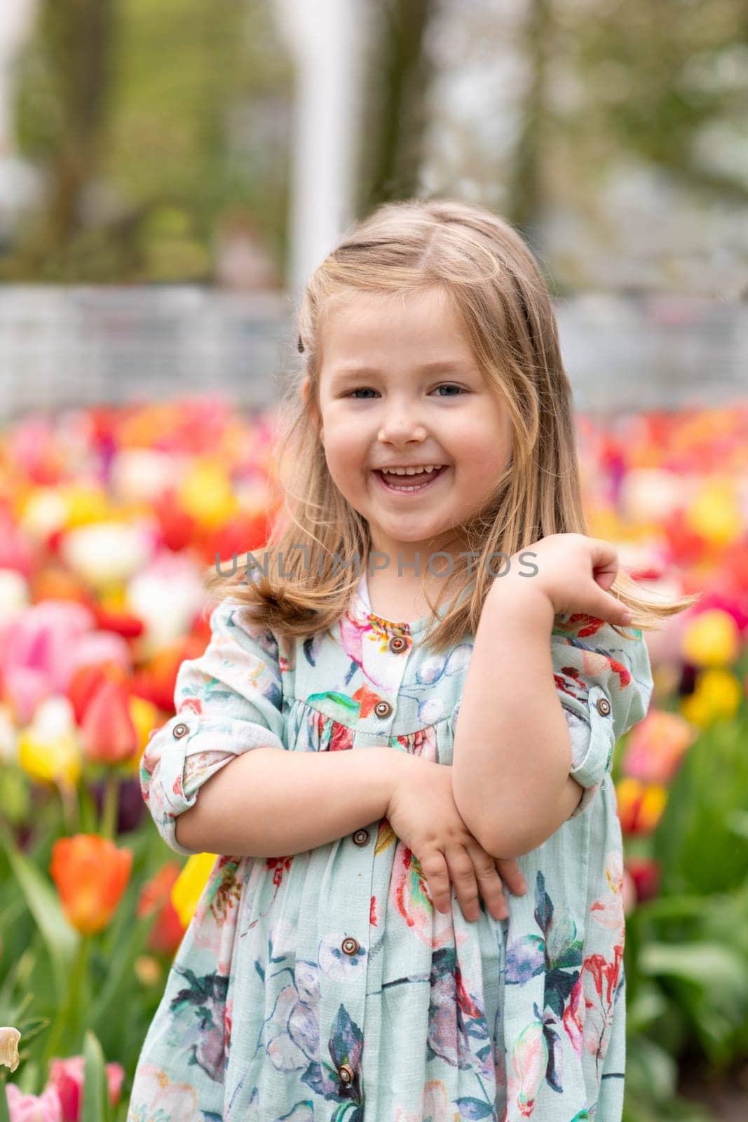 Happy girl laughs in a park with the tulips