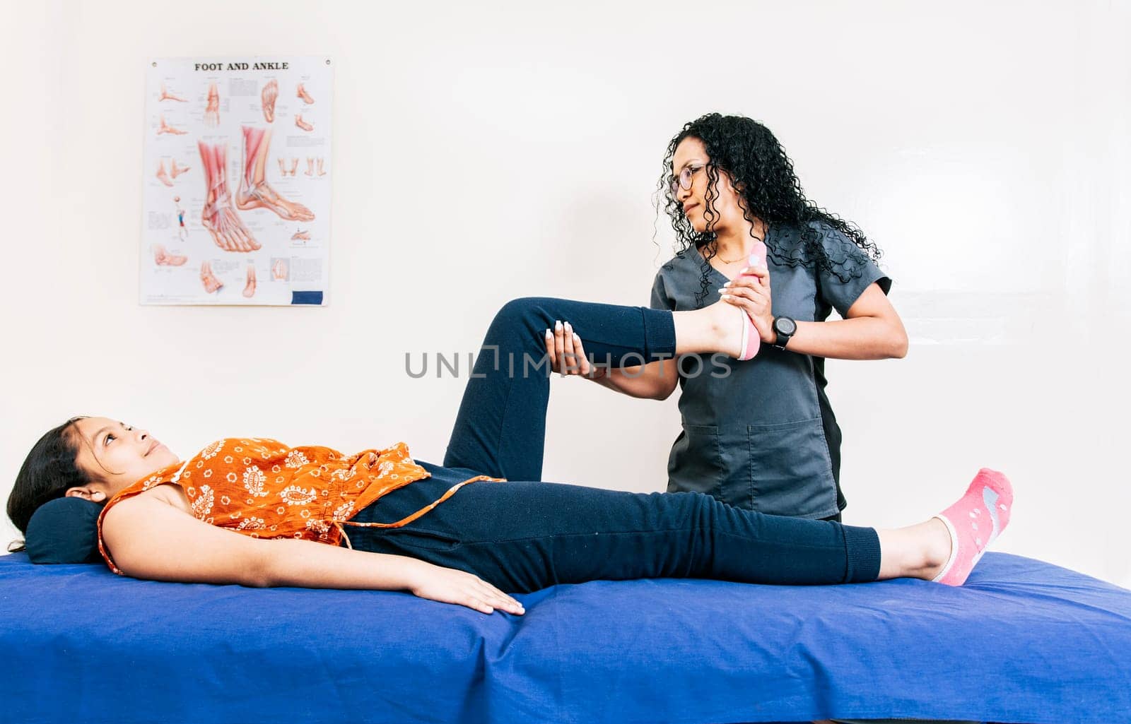 Professional physiotherapist assisting patient in leg rehabilitation. Modern leg rehabilitation physiotherapy. Worker in modern physiotherapy assisting female patient.