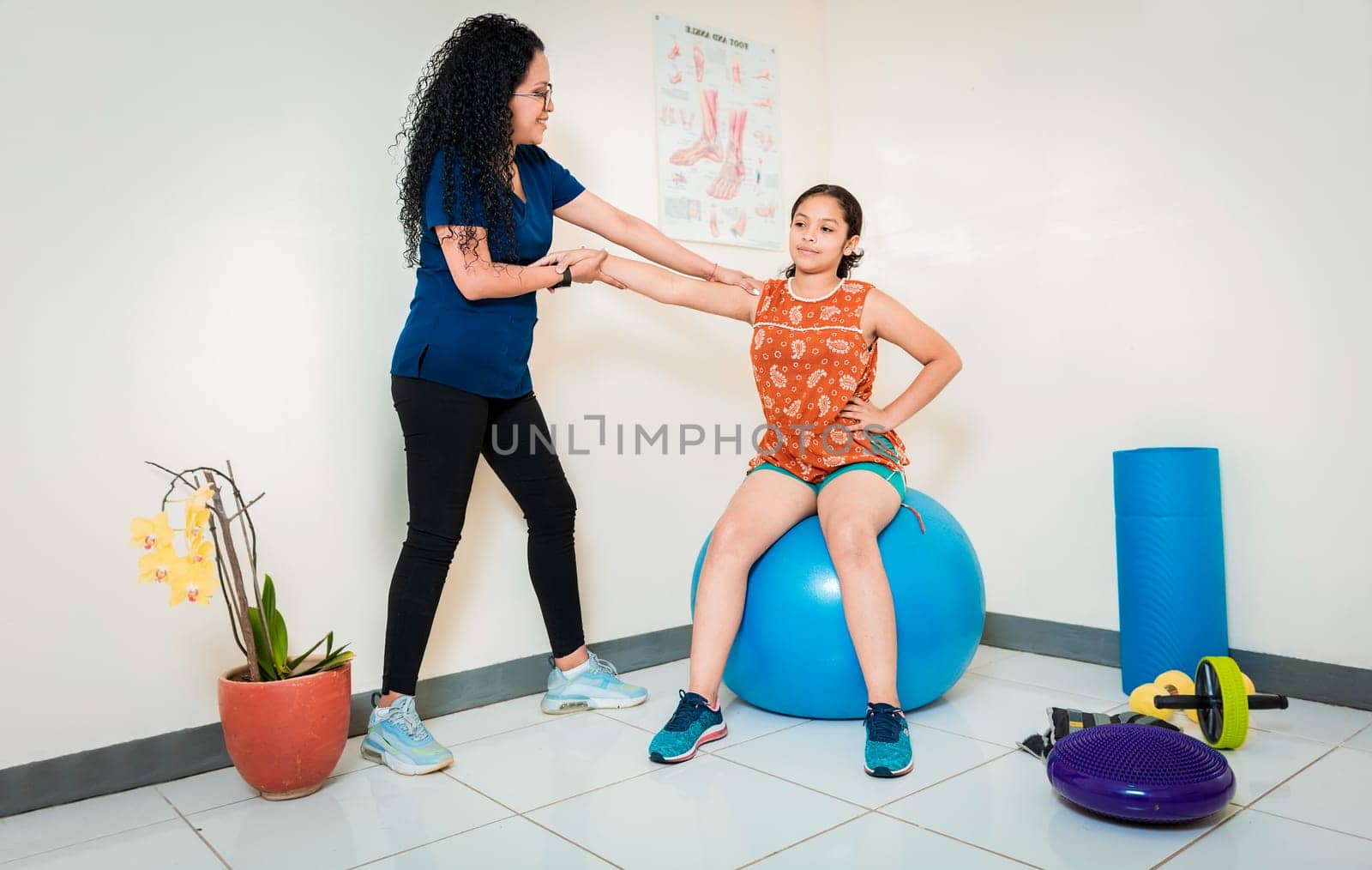 Physiotherapist assisting female patient sitting on rehabilitation ball. Rehabilitation therapy with fitness ball, Physiotherapist woman with patient sitting on rehabilitation ball