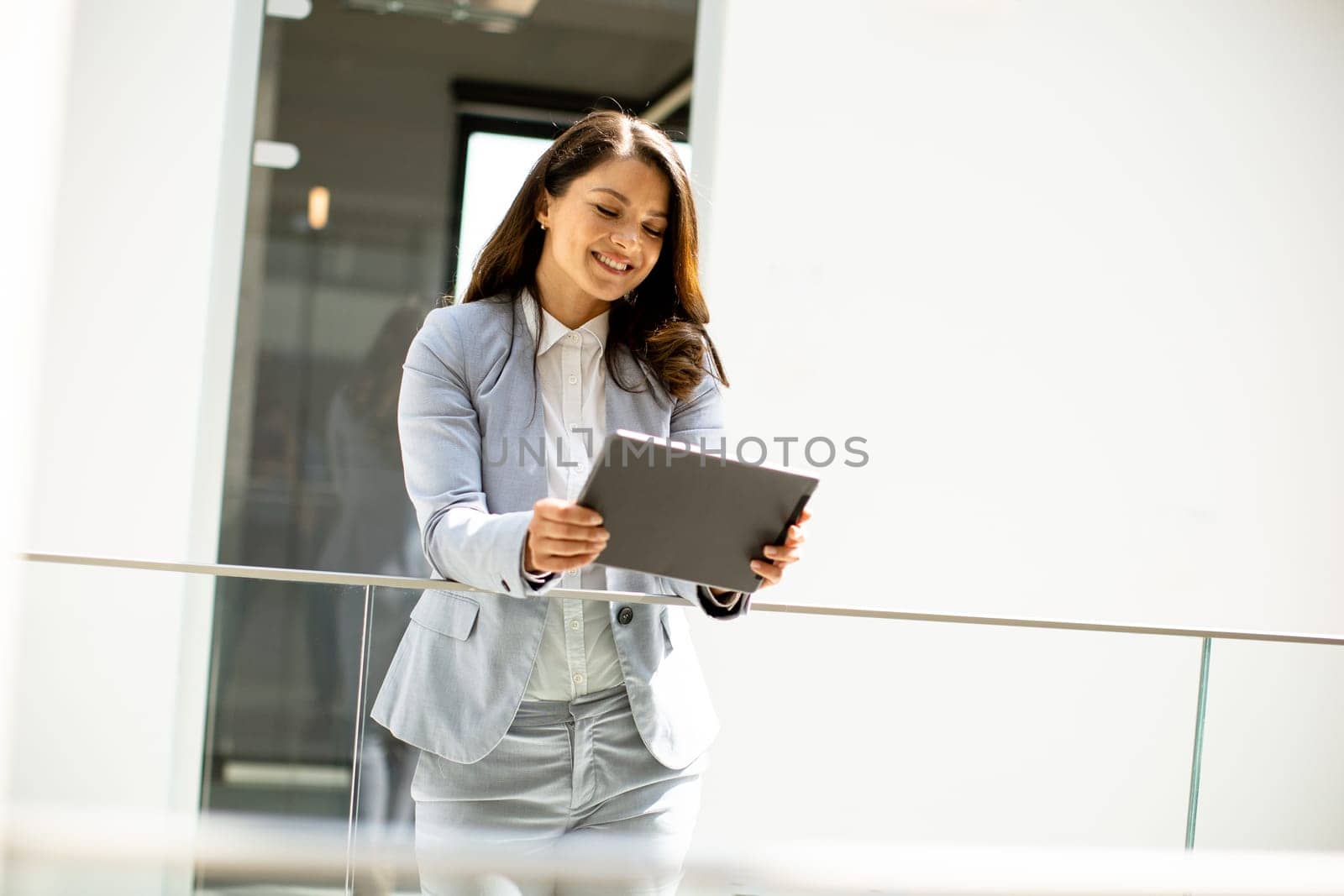 Pretty young woman working on digital tablet in the office hallway