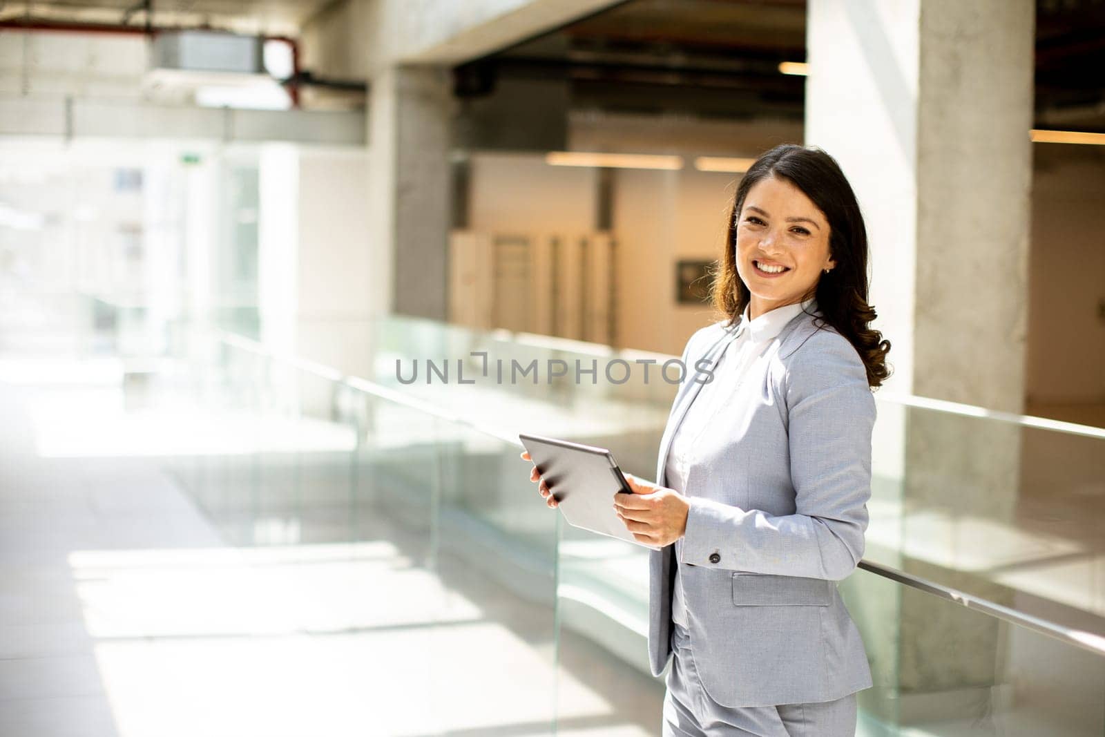 Pretty young woman working on digital tablet in the office hallway