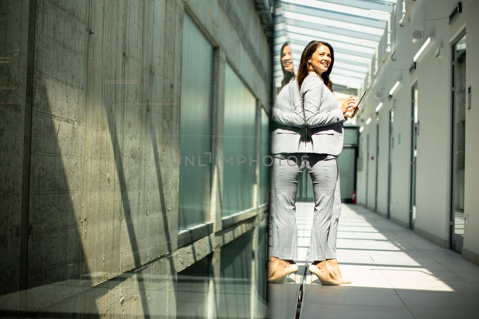 Pretty young woman working on digital tablet in the office hallway