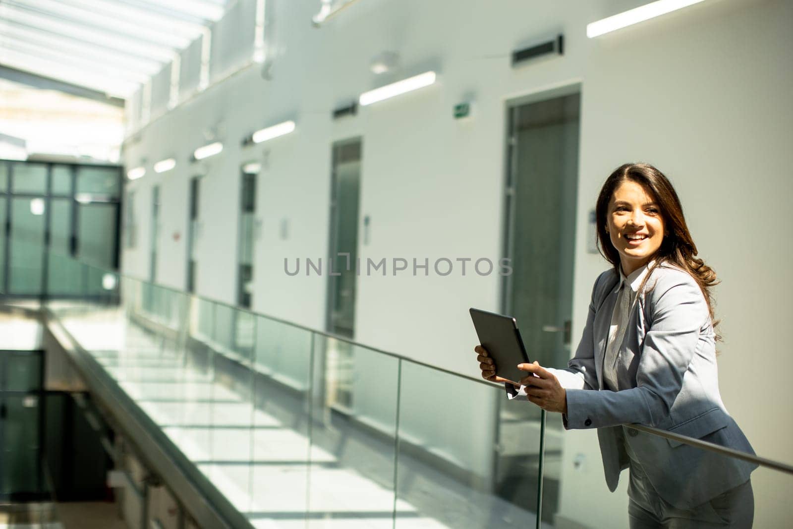 Pretty young woman working on digital tablet in the office hallway