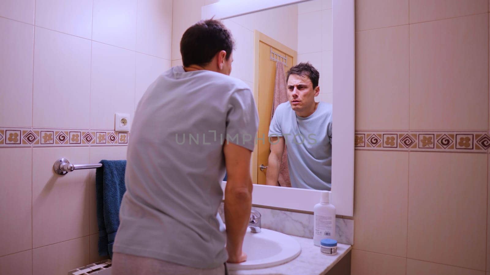 Man looking at his reflection in the bathroom mirror on monday morning, feeling tired and not wanting to go to work