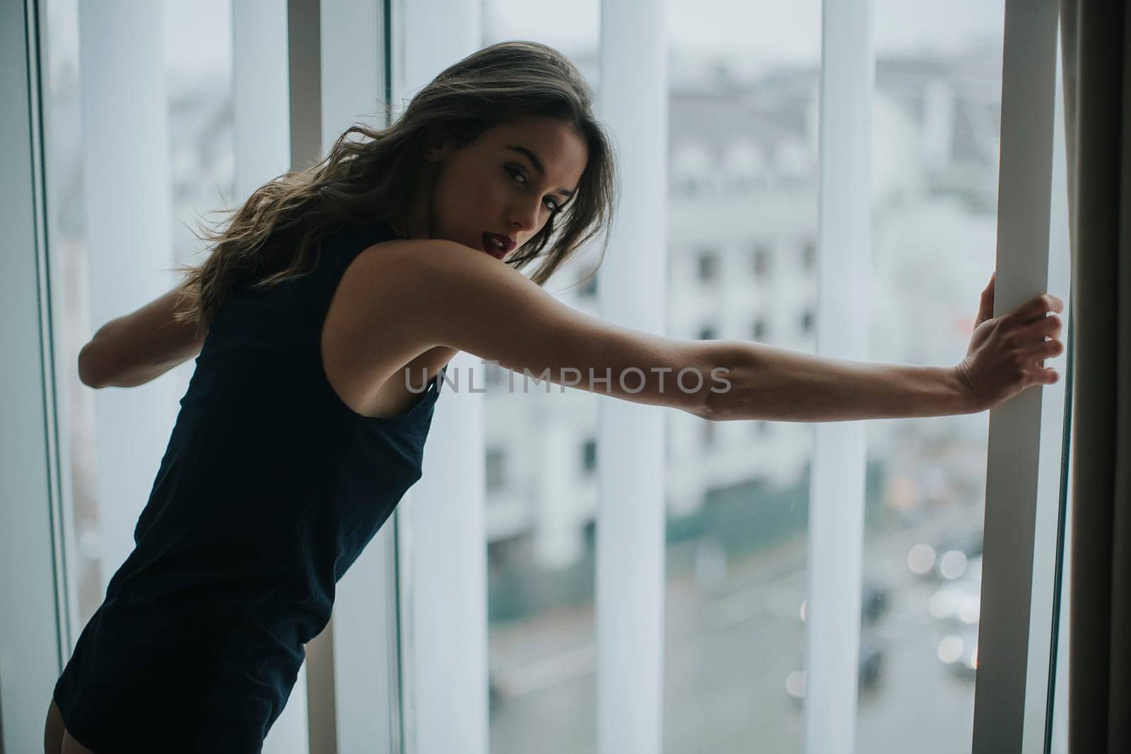 Pretty young woman in underwear standing by window in the room