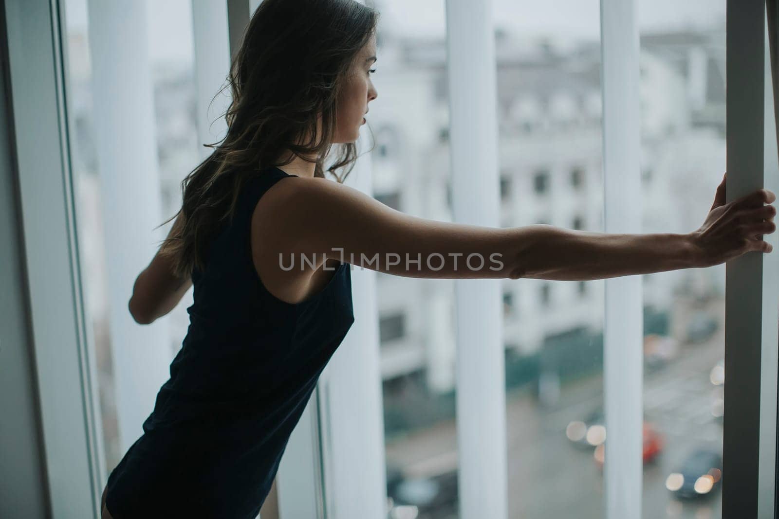 Pretty young woman in underwear standing by window in the room