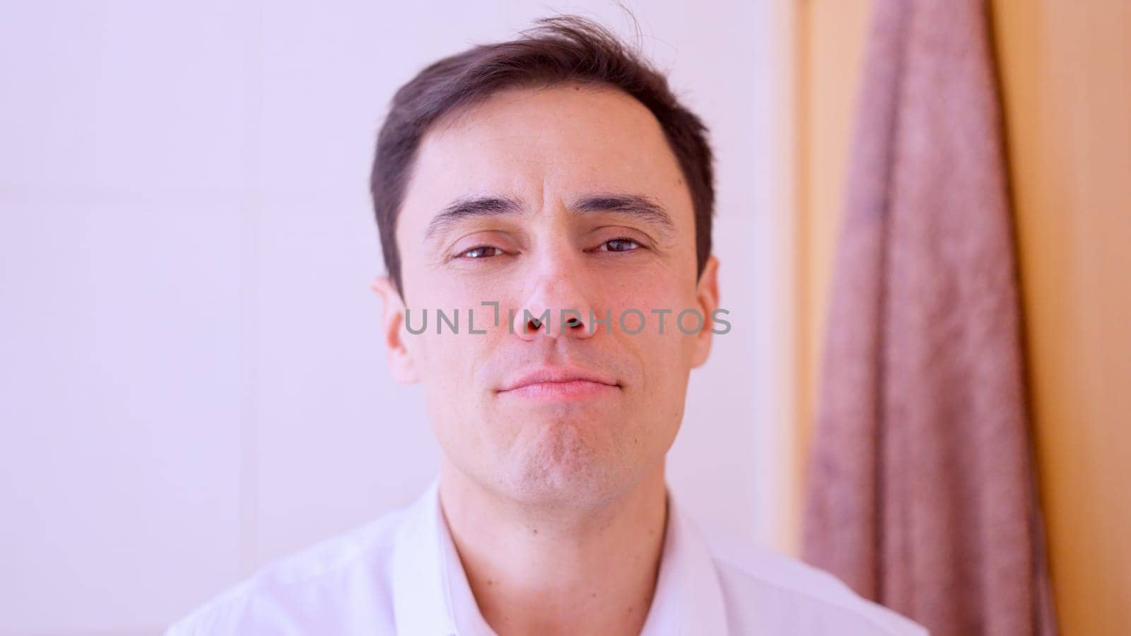 Confident businessman smiling while looking at mirror in bathroom, getting ready for work