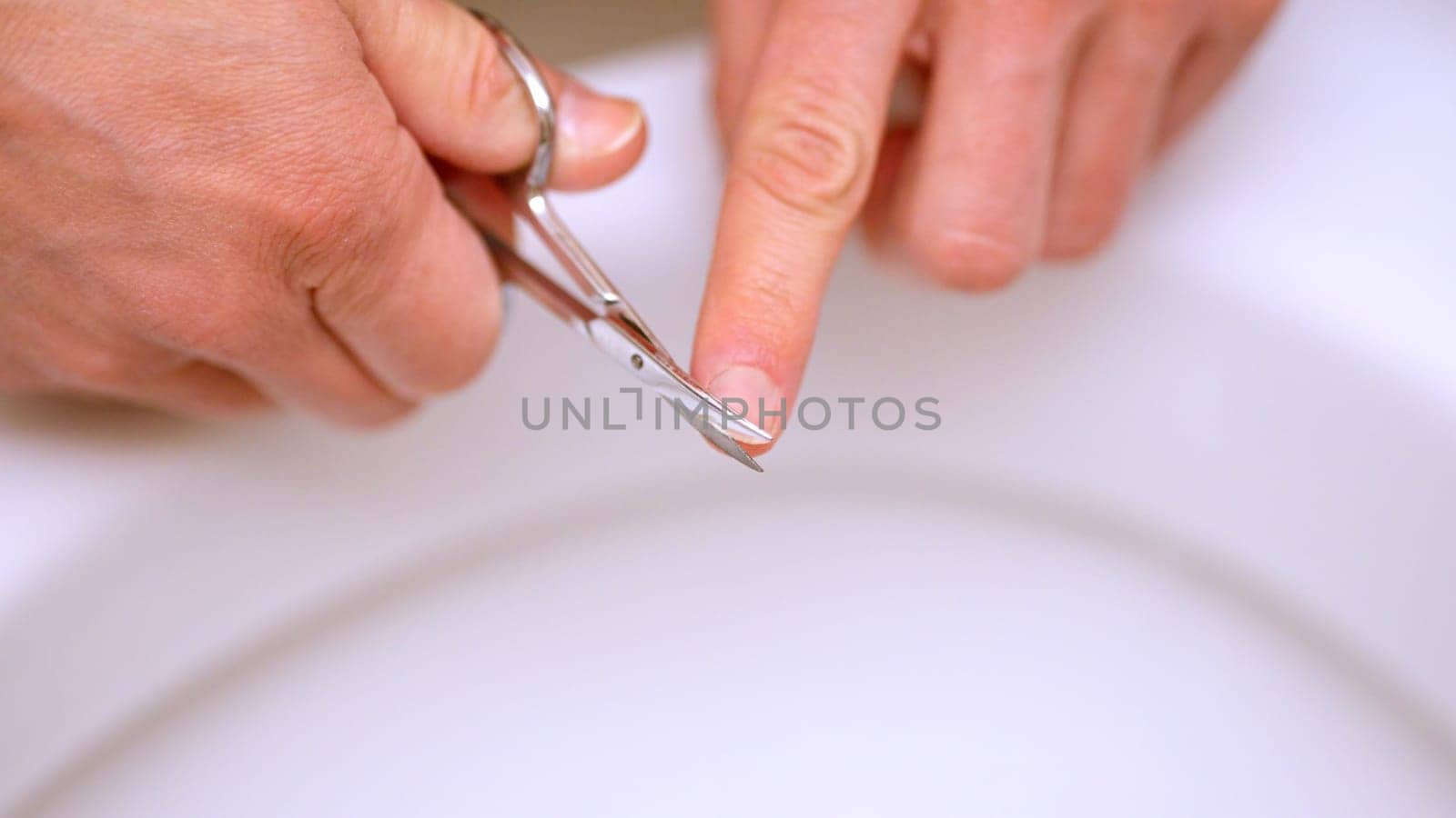 Close up of hands using manicure scissors for nail trimming, personal hygiene and beauty care