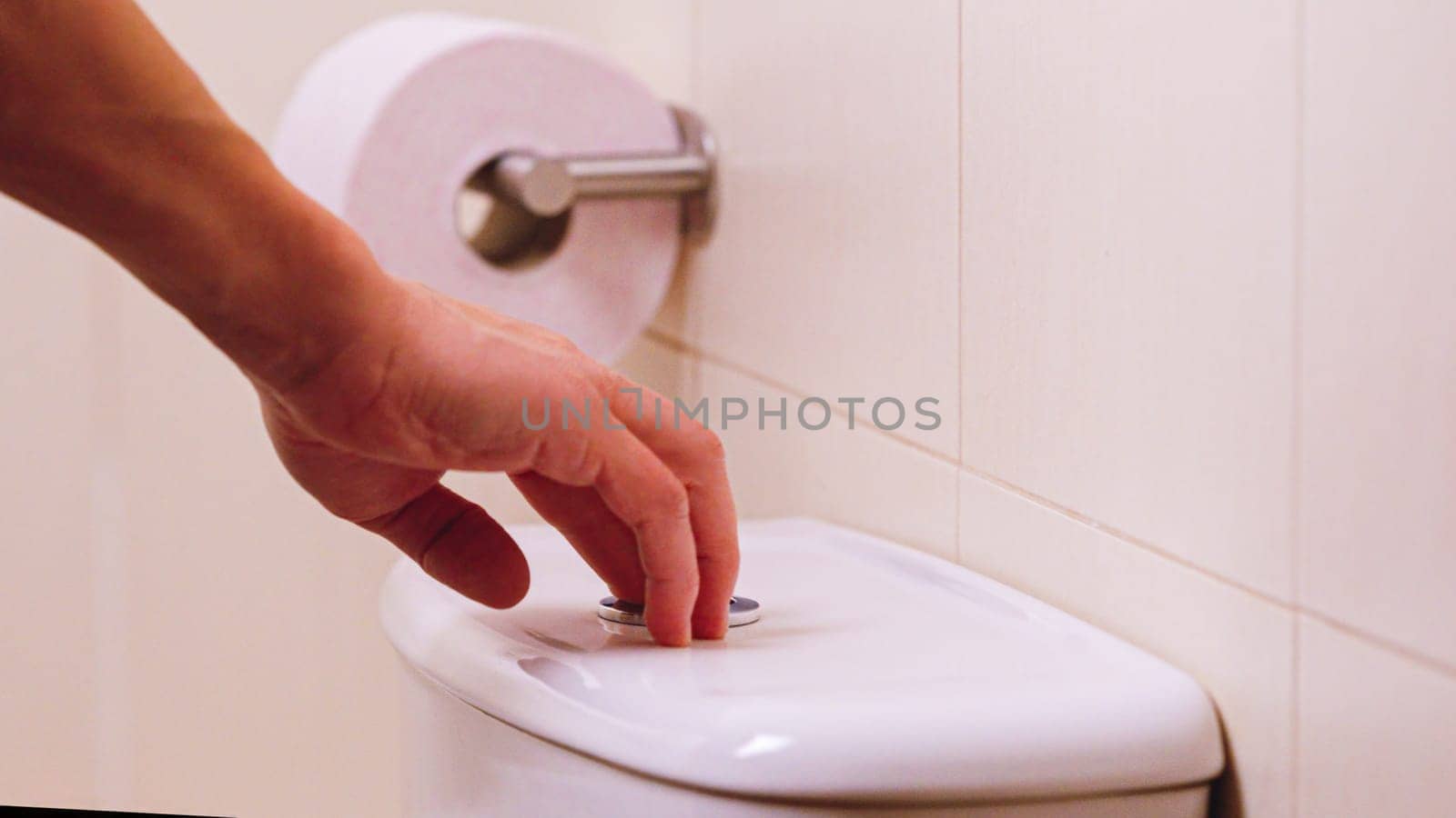 Close up of a hand flushing a white toilet