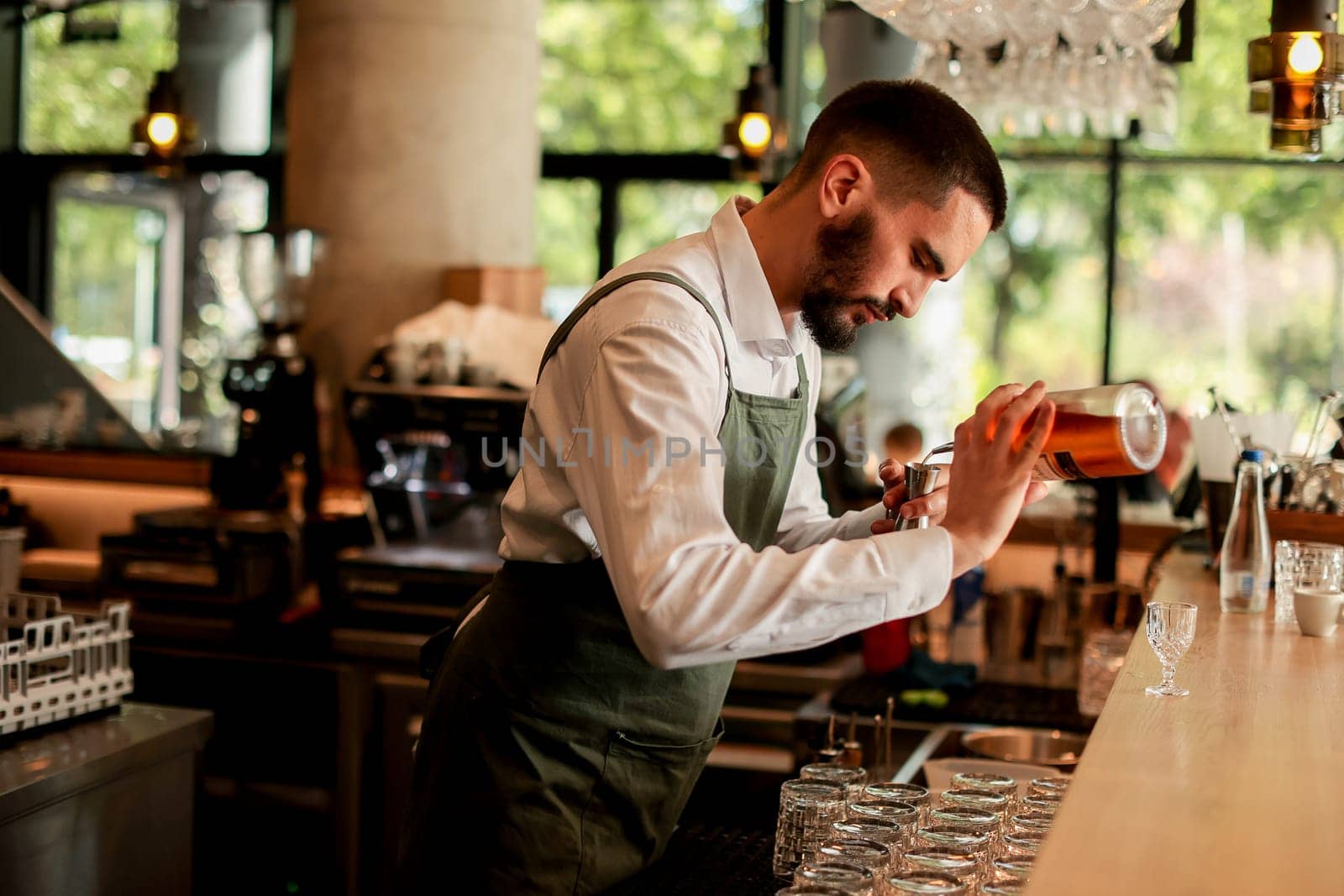 In a lively bar setting, a confident bartender mixes a fresh cocktail, showcasing his expertise with a bottle in hand, ready for the night's rush