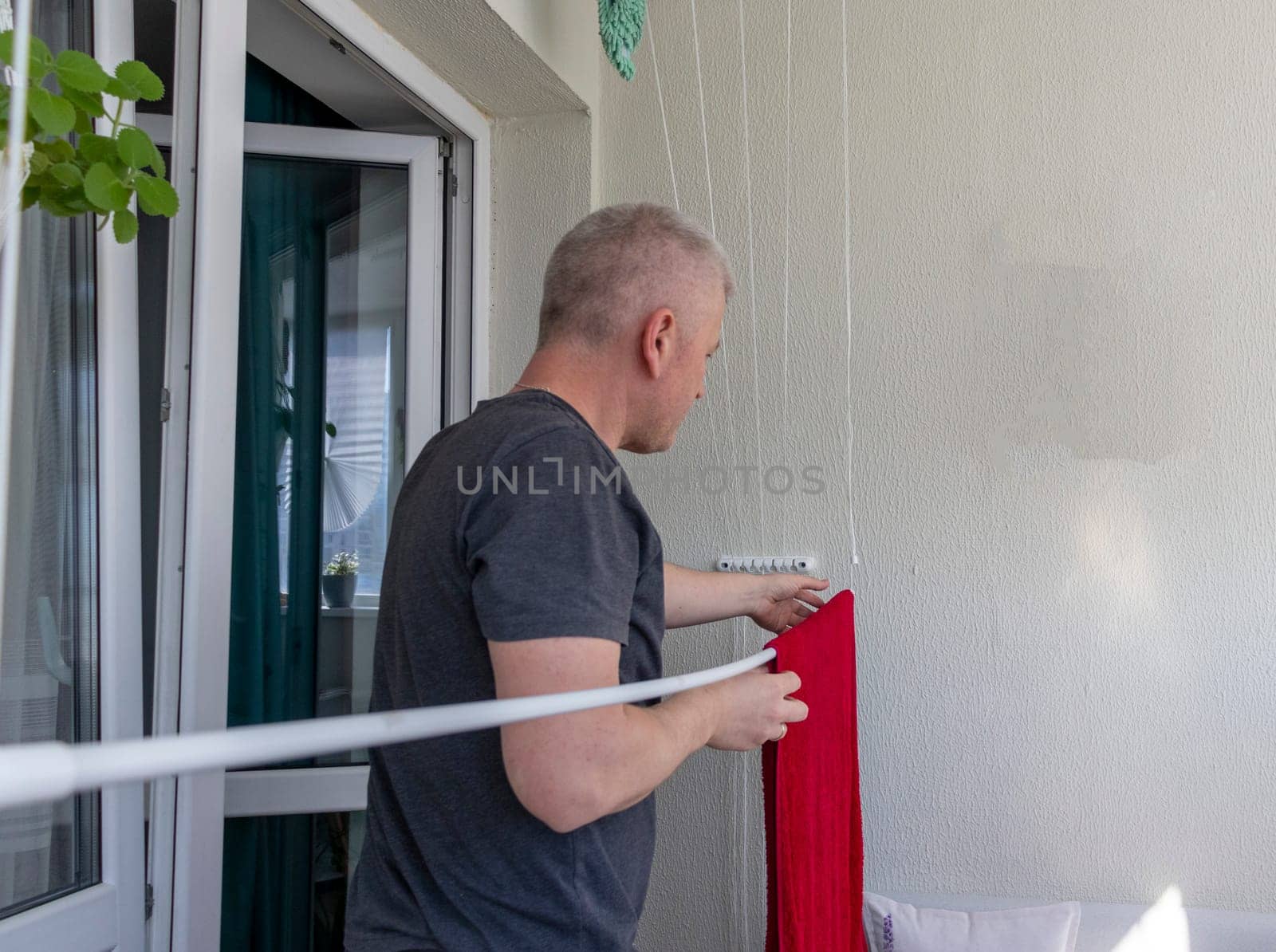 Man hangs the clothes on the roller dryer on the balcony