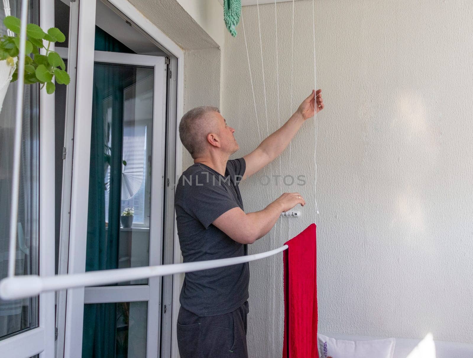 Man hangs the clothes on the roller dryer on the balcony