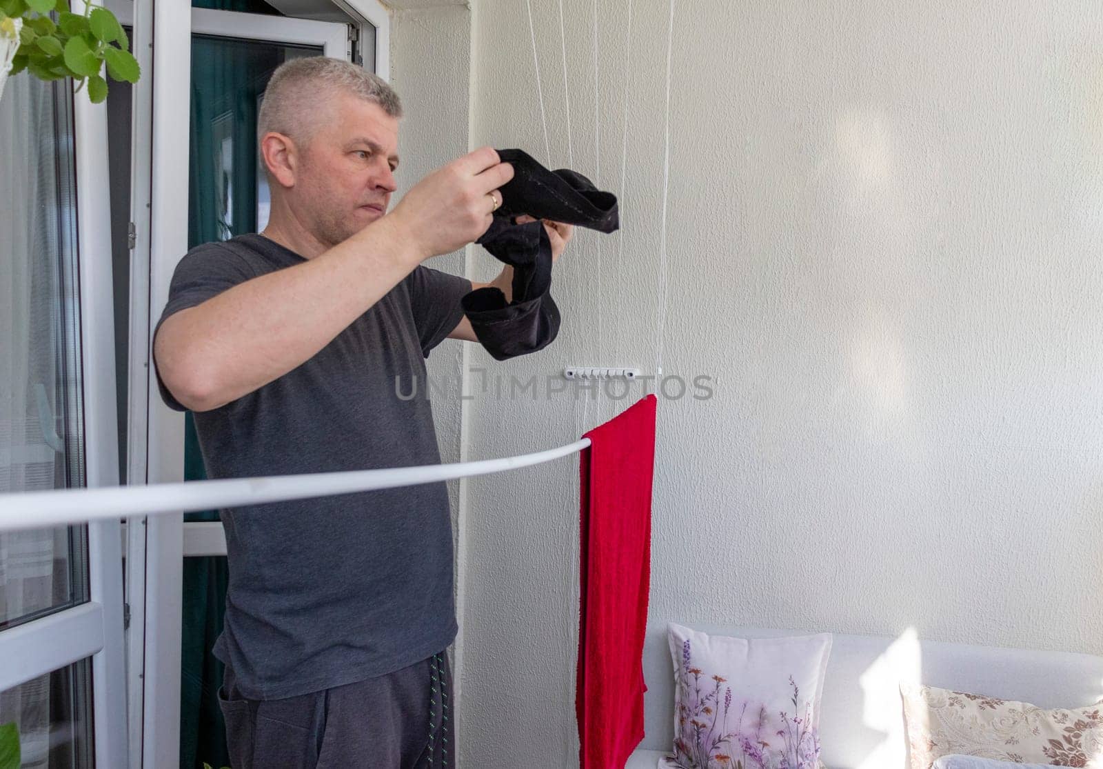 Man hangs the clothes on the roller dryer on the balcony