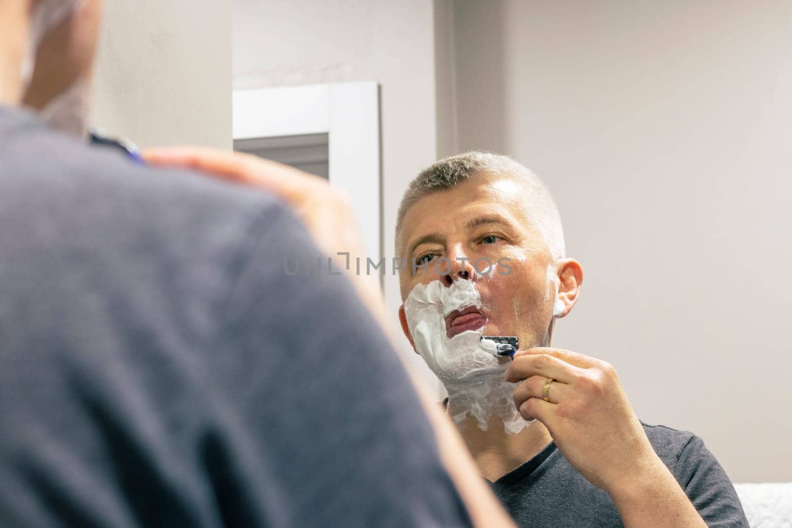 Reflection in the mirror of the man shaving