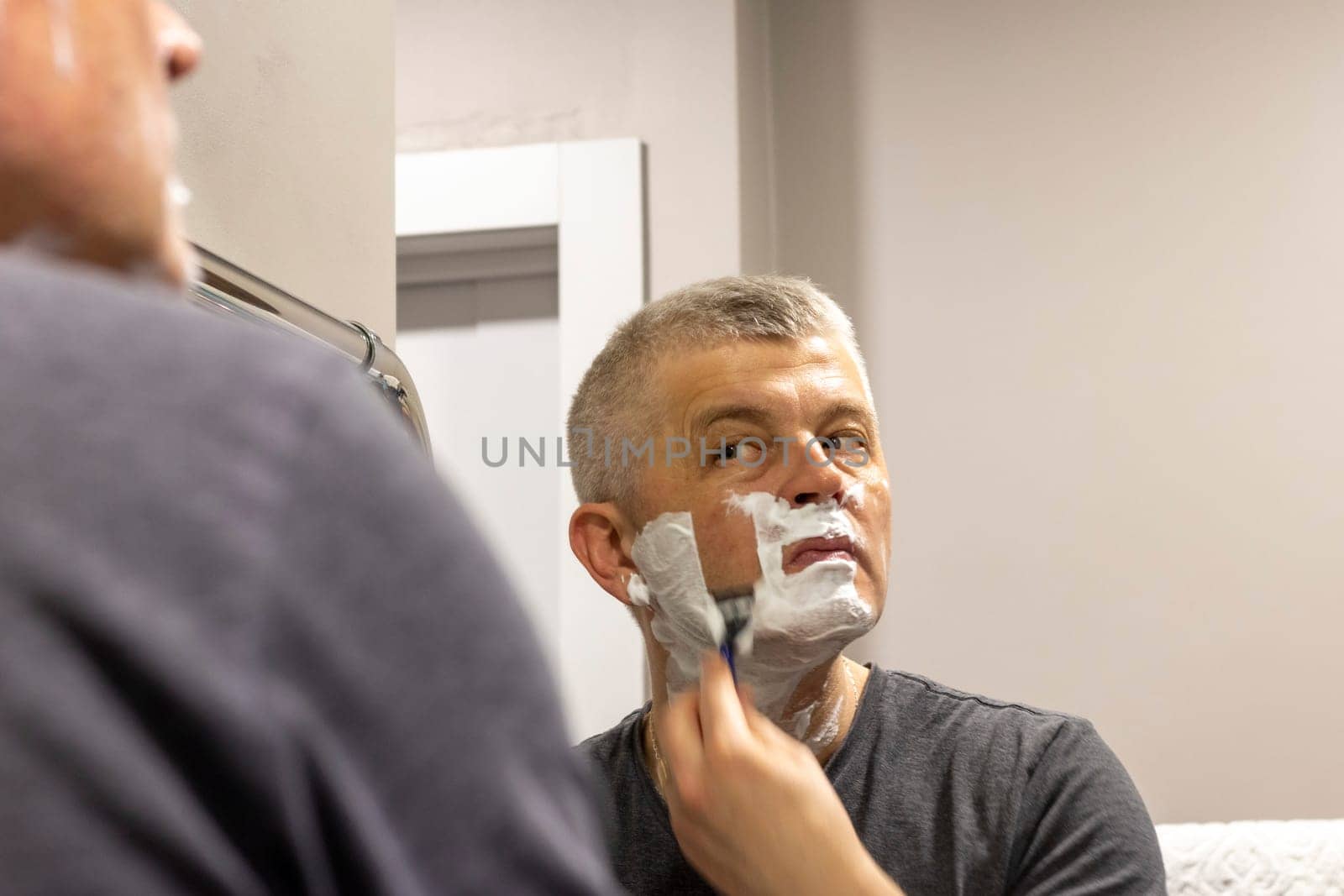 Reflection in the mirror of the man shaving
