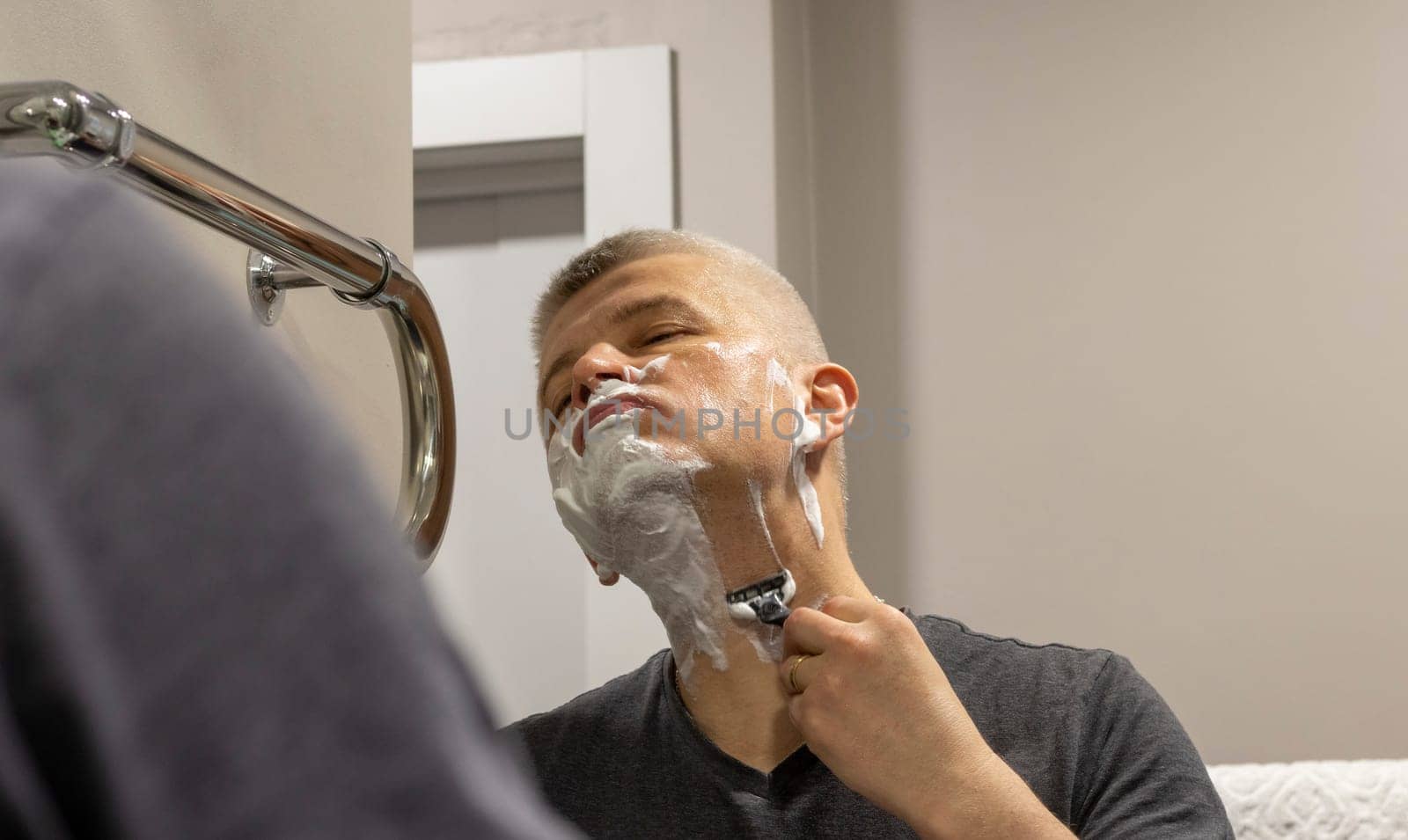 Reflection in the mirror of the man shaving