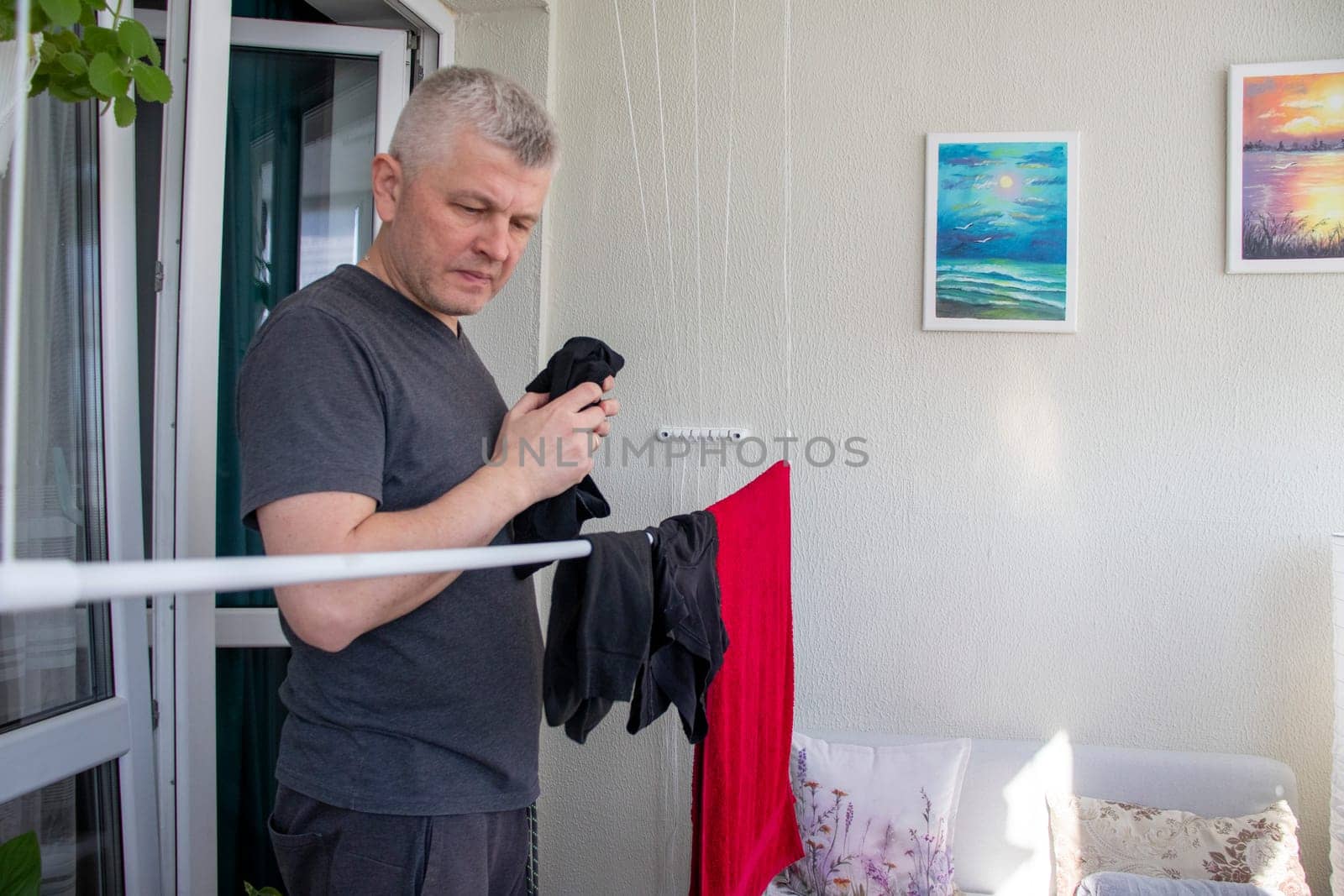 Man hangs the clothes on the roller dryer on the balcony.