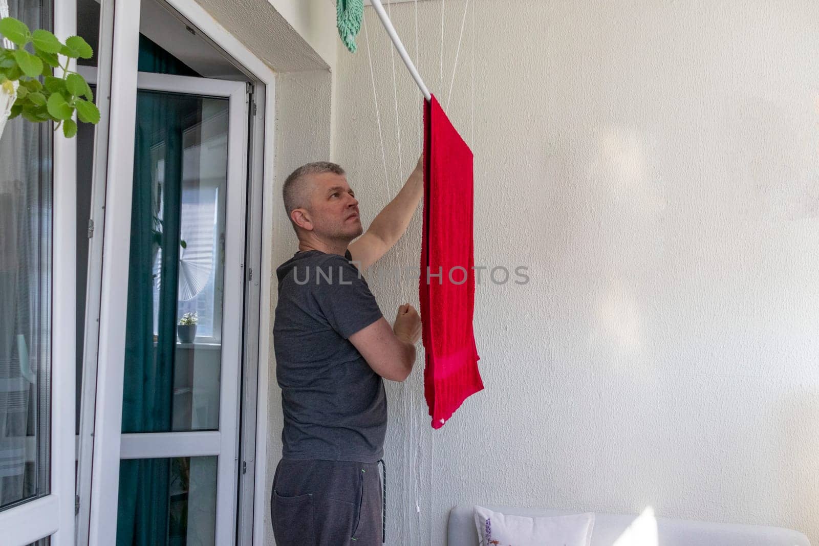 Man hangs the clothes on the roller dryer on the balcony
