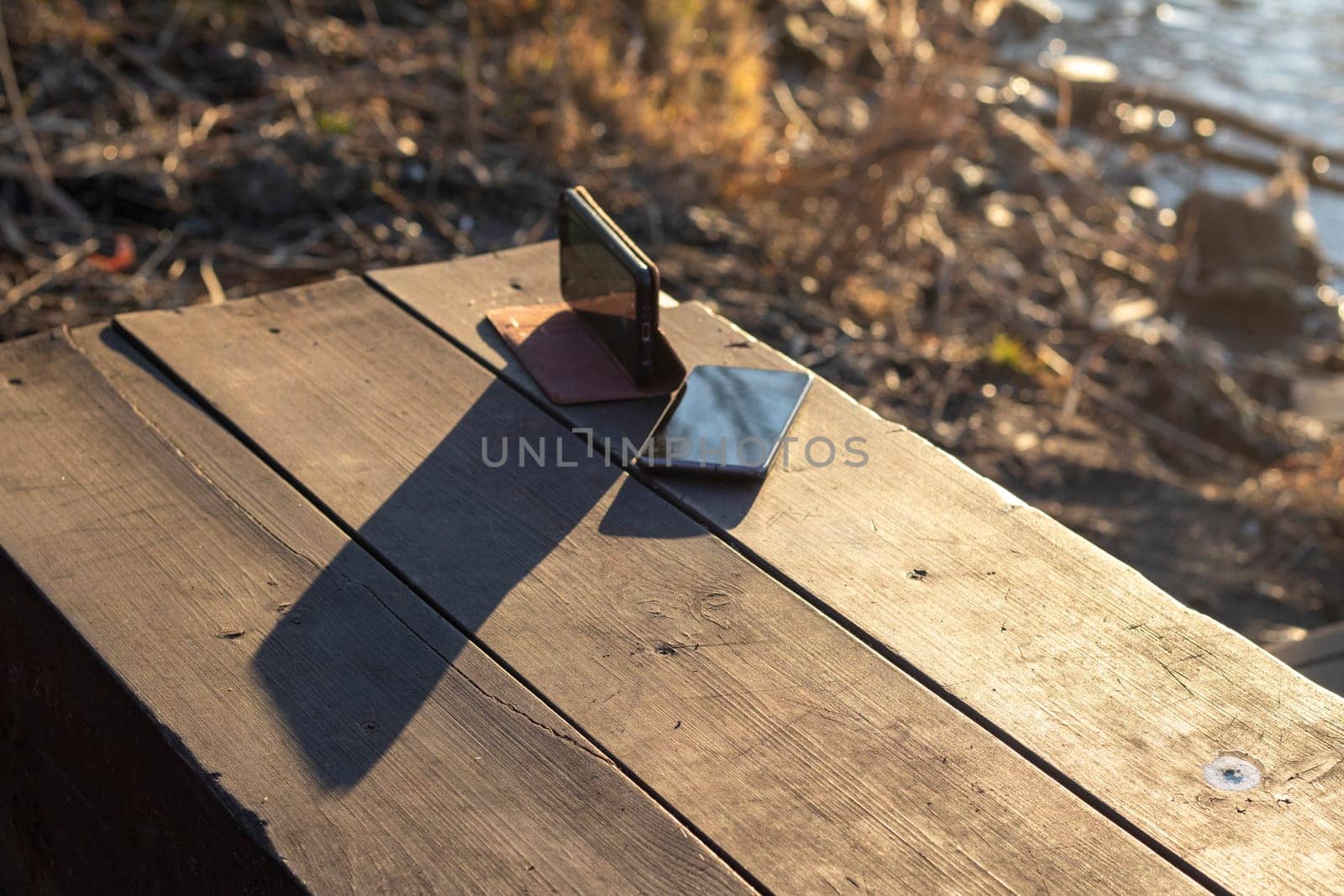 Shot of the two mobile phones on the wooden bench