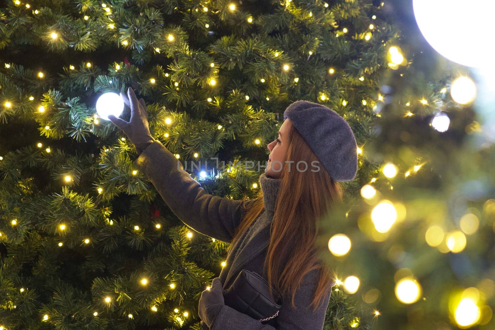 In her grey coat and iconic beret, a Parisian woman gazes fondly at Christmas decorations on a tree, surrounded by the enchanting spirit of New Year festivities in a wintry Paris setting